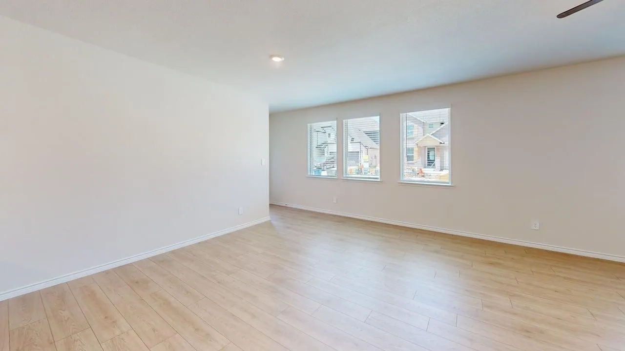 Expansive room featuring wood-finish flooring, white baseboards, and neutral wall paint
