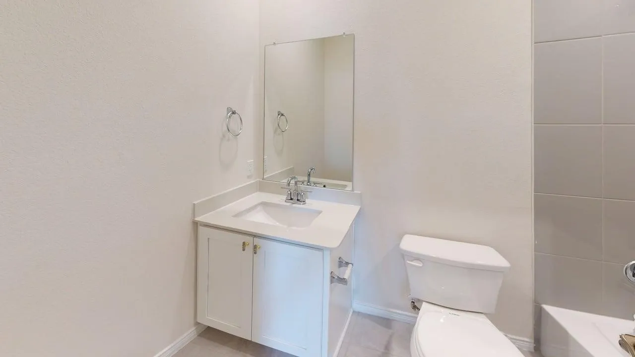 White vanity with integrated sink, chrome faucet, and rectangular mirror