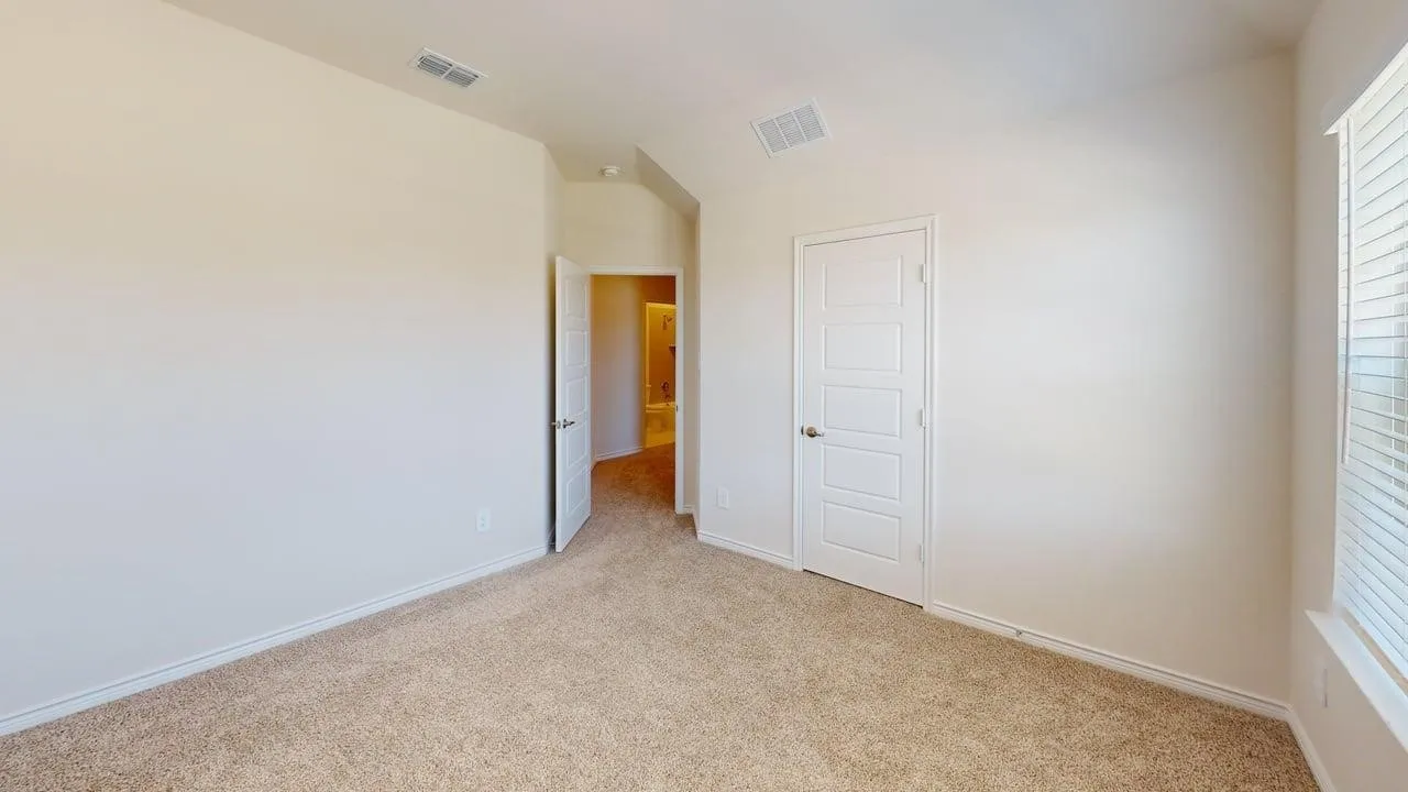 Carpeted room featuring light-toned walls, white trim, a multi-panel door, and a window with horizontal blinds