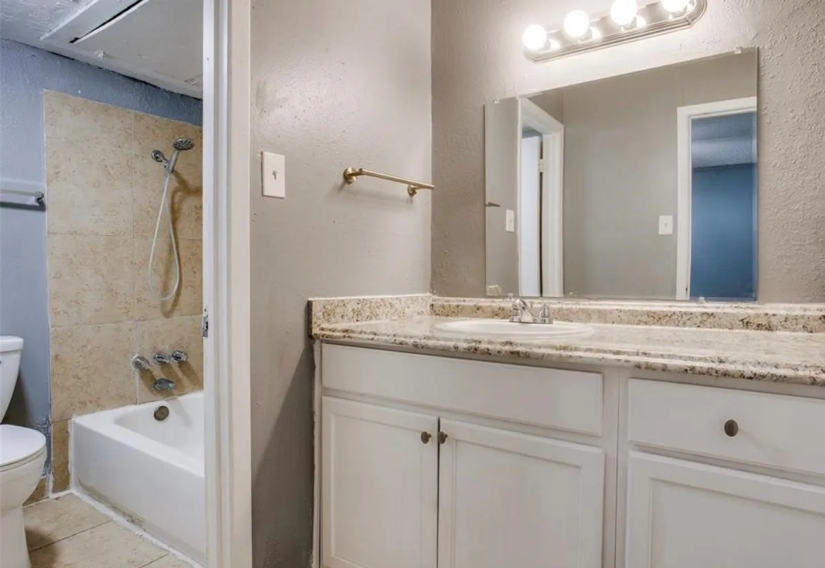 Bathroom featuring a white vanity with a light-toned countertop, an integrated sink, and an expansive mirror