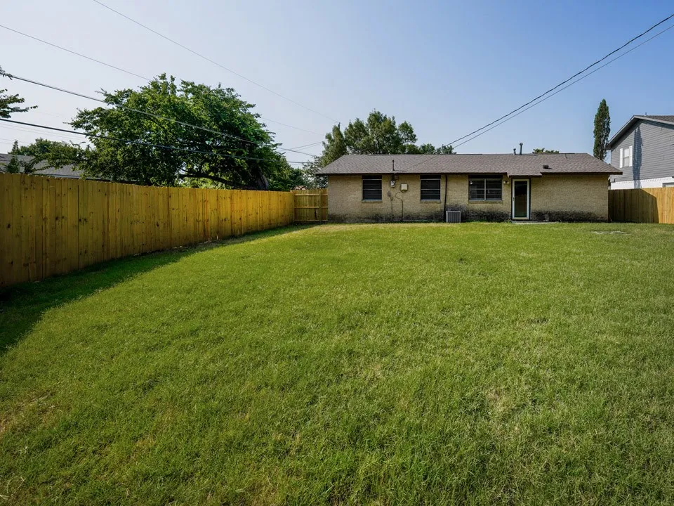 Expansive grass lawn with a full-height wood plank privacy fence