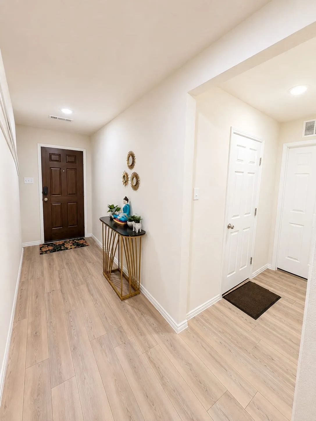Spacious entry hall featuring light wood-finish flooring, crisp white baseboards, and a recessed ceiling light