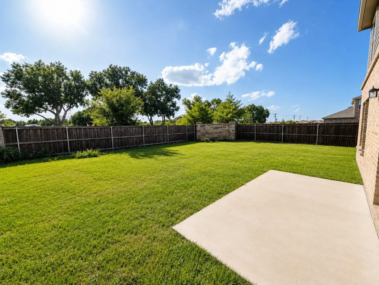 Expansive backyard featuring a lush green lawn and a concrete patio