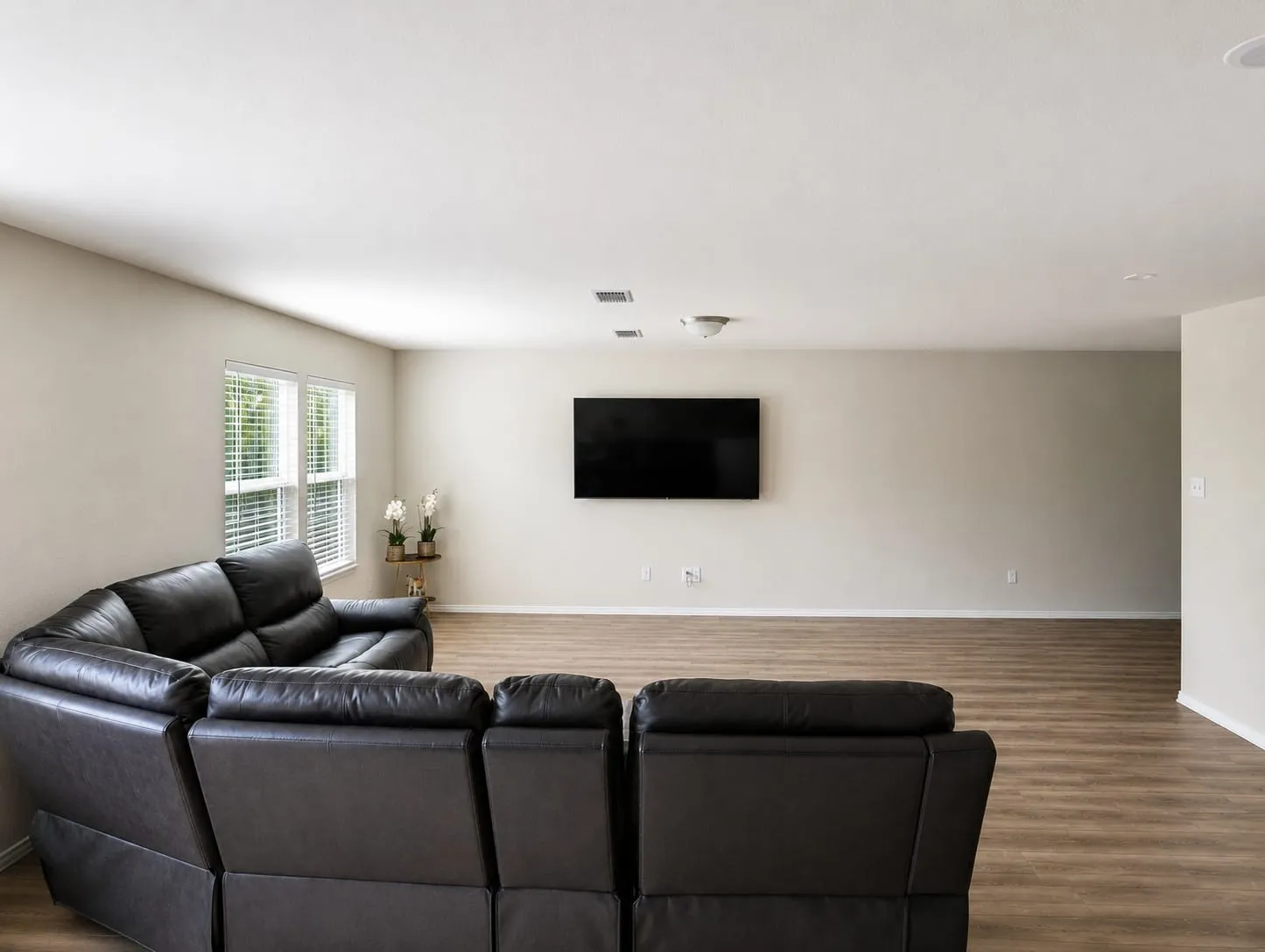 Spacious living area featuring wood-finish flooring, neutral wall tones, and recessed lighting