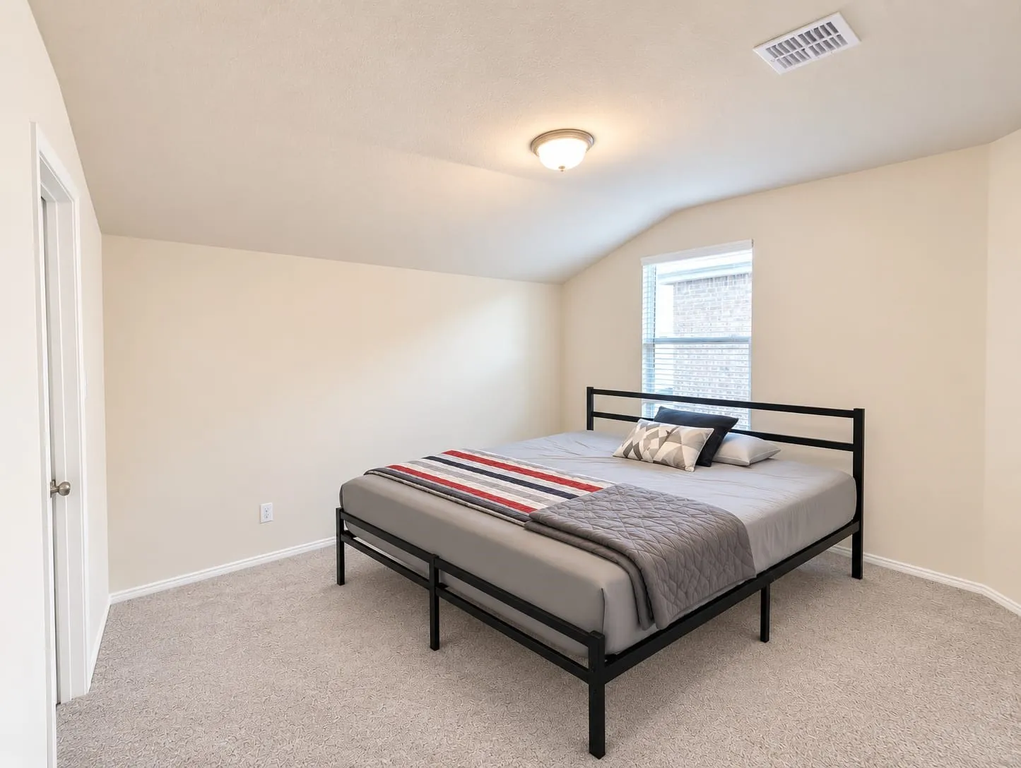 Carpeted room featuring a window with blinds, a white door, and a ceiling light fixture