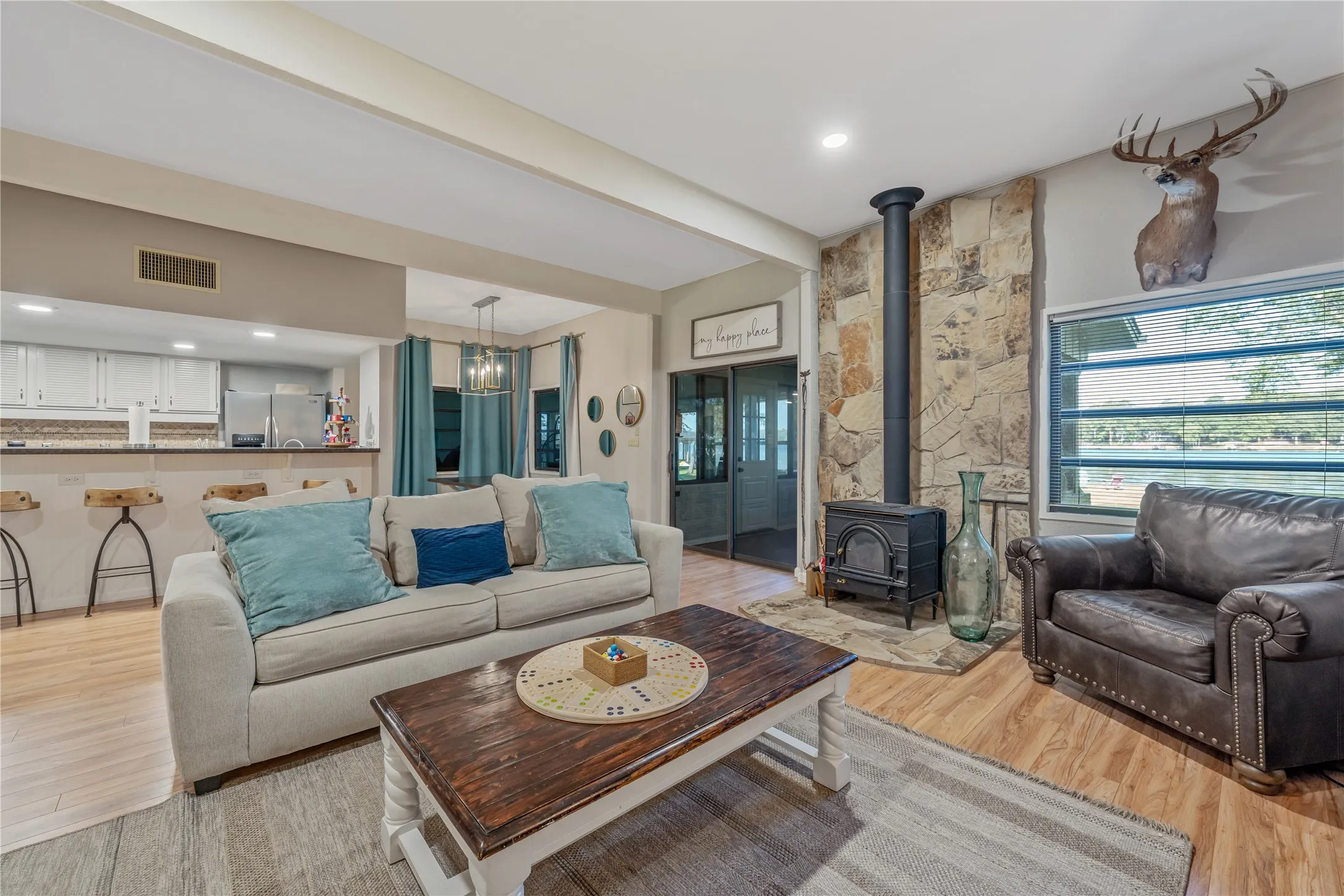 Spacious living area featuring wood-finish flooring, a stone accent wall, and a built-in wood-burning stove