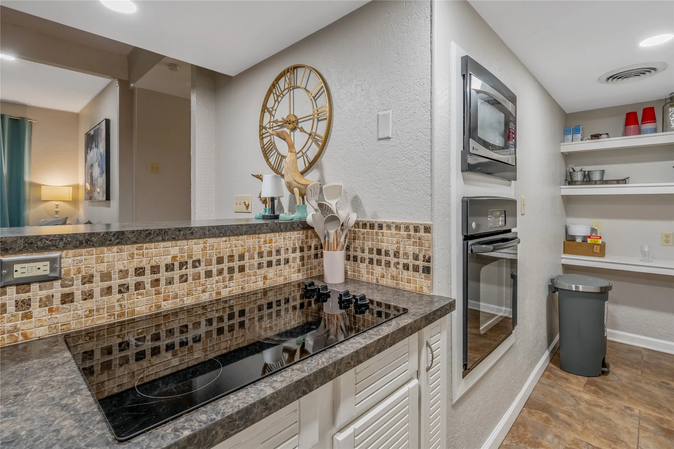 Kitchen featuring a smooth-top electric cooktop, built-in microwave, wall oven, mosaic tile backsplash, and open shelving