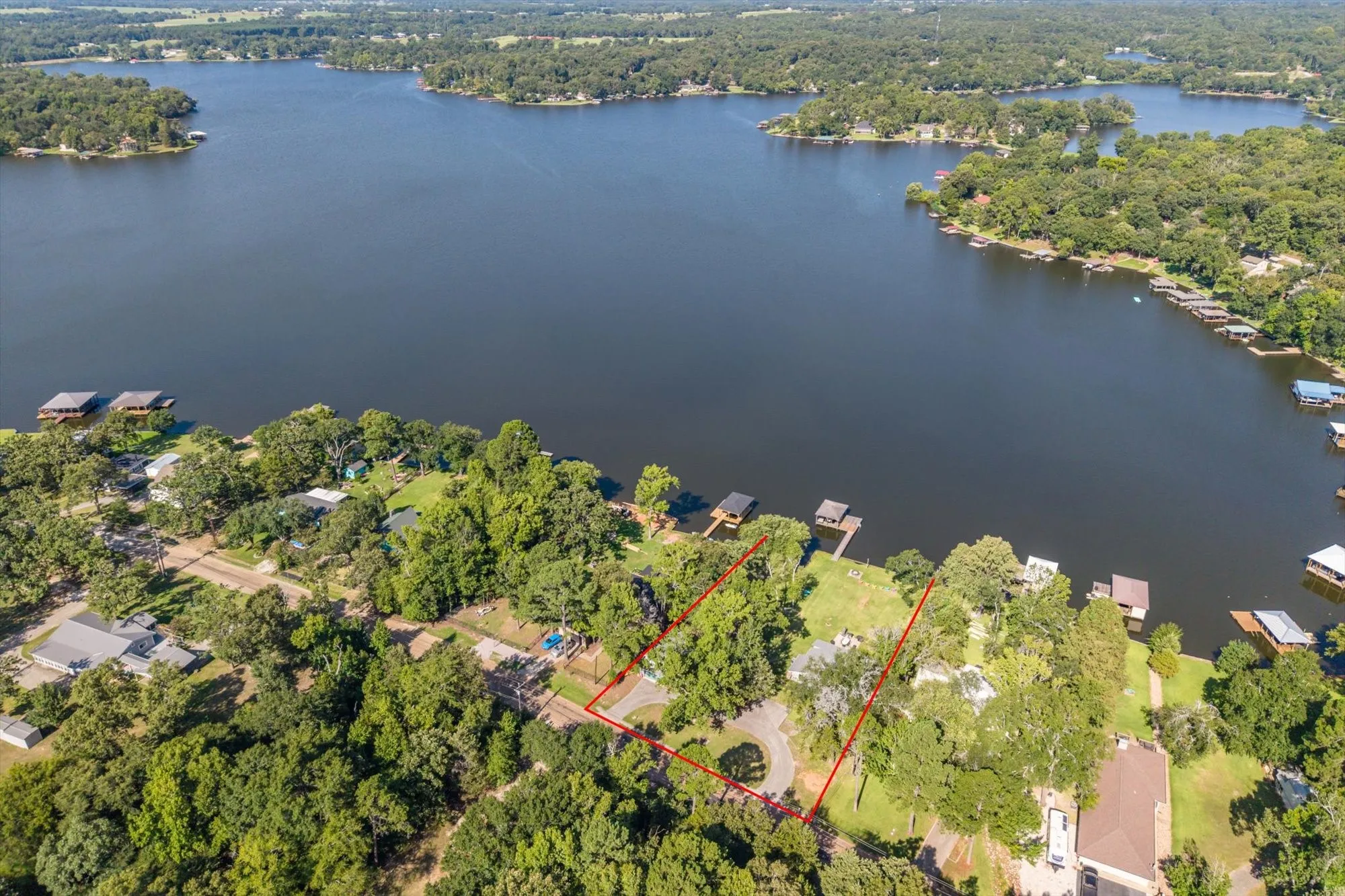 Expansive waterfront property featuring a substantial lakefront, mature tree coverage, and an established residential setting