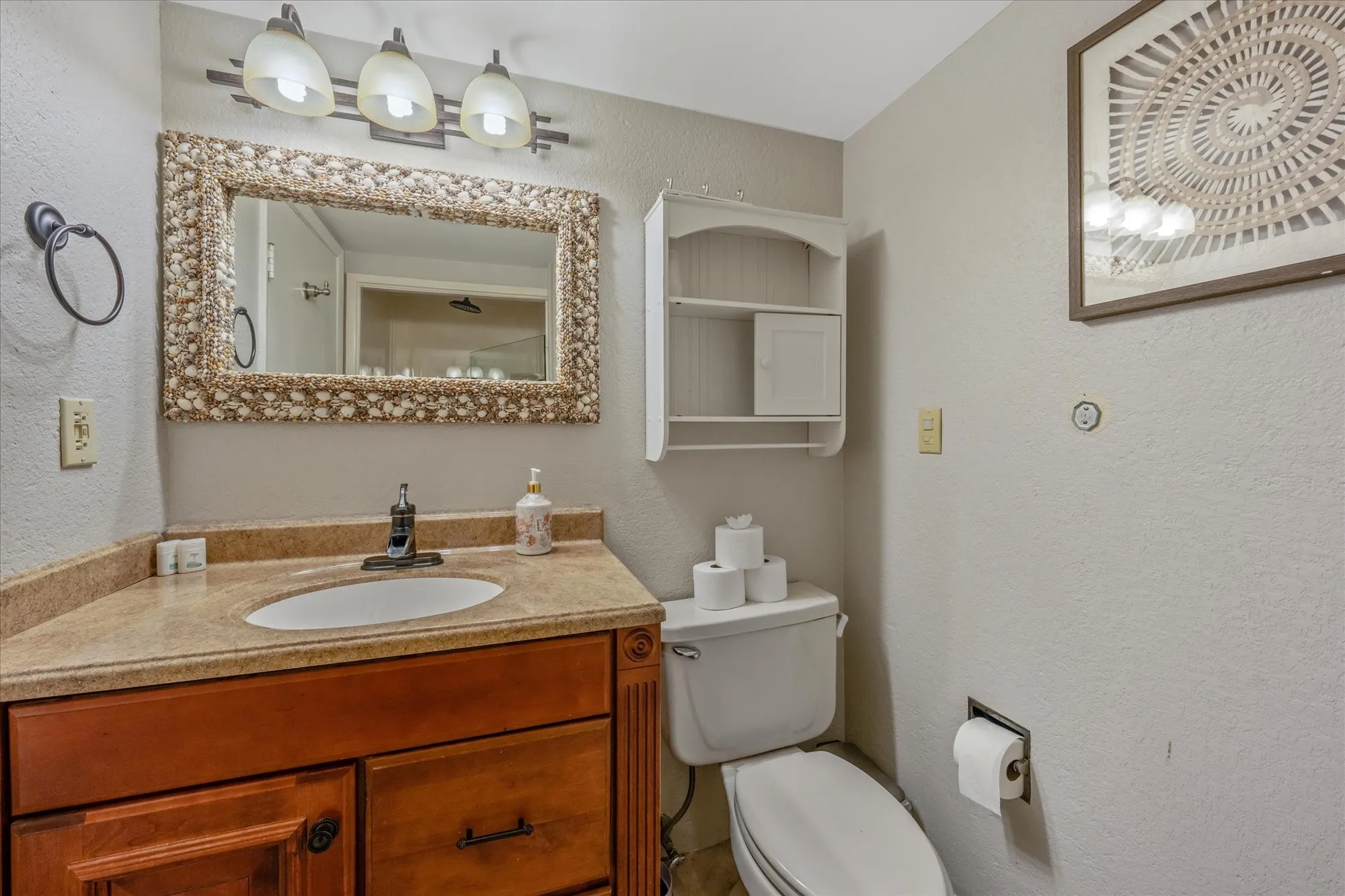 Bathroom with a wood-finish vanity featuring a built-in sink and a stone-finish countertop