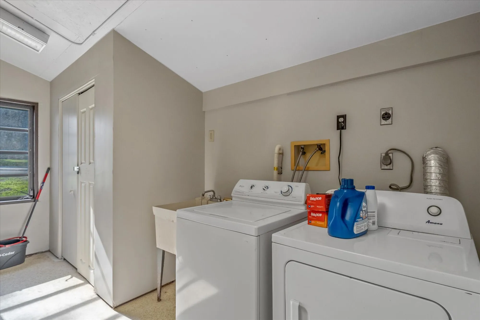 Dedicated laundry area featuring a utility sink, a window, and a storage closet