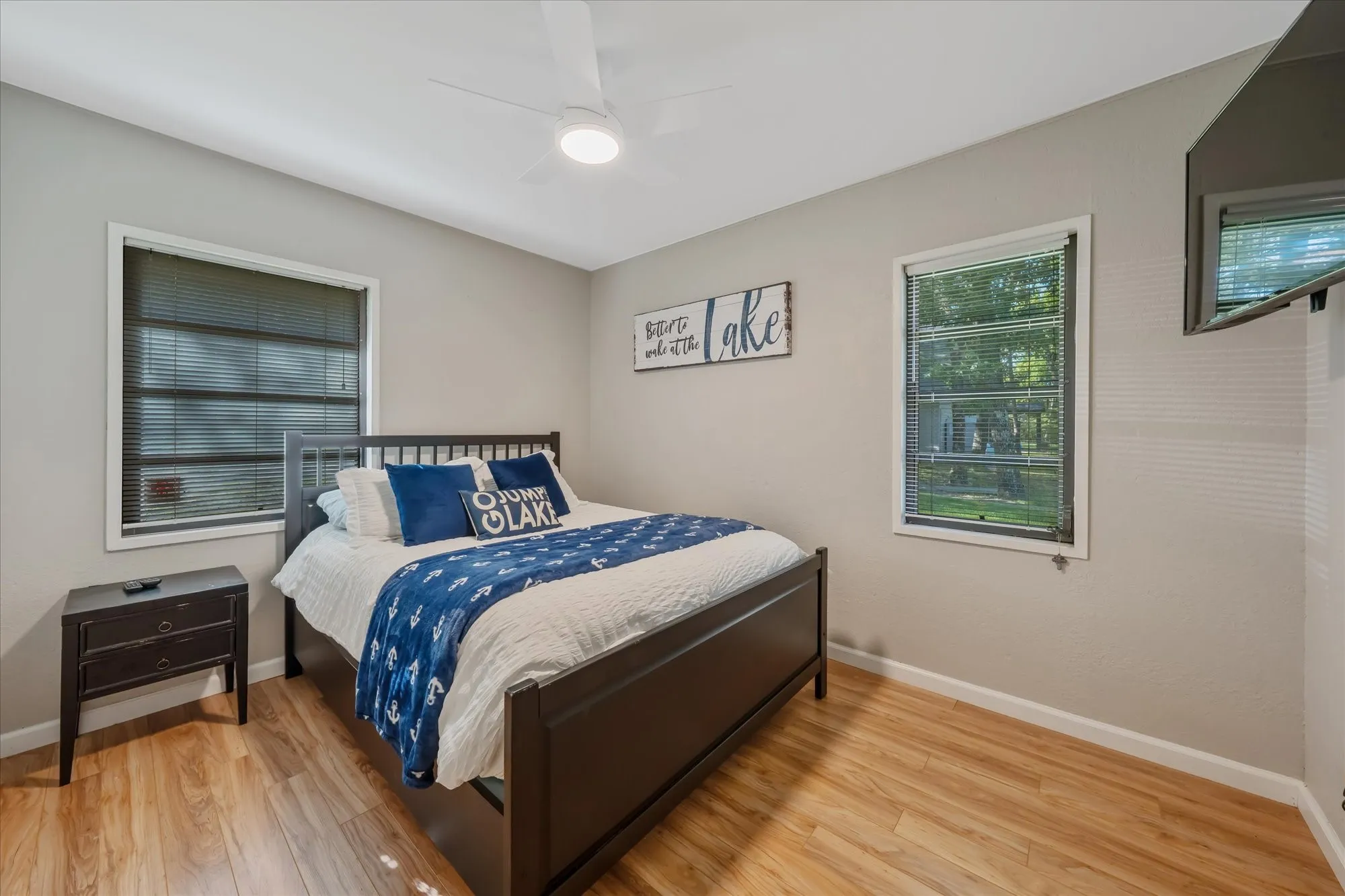 Spacious room featuring light wood-finish flooring, neutral wall tones, and a ceiling fan with integrated lighting