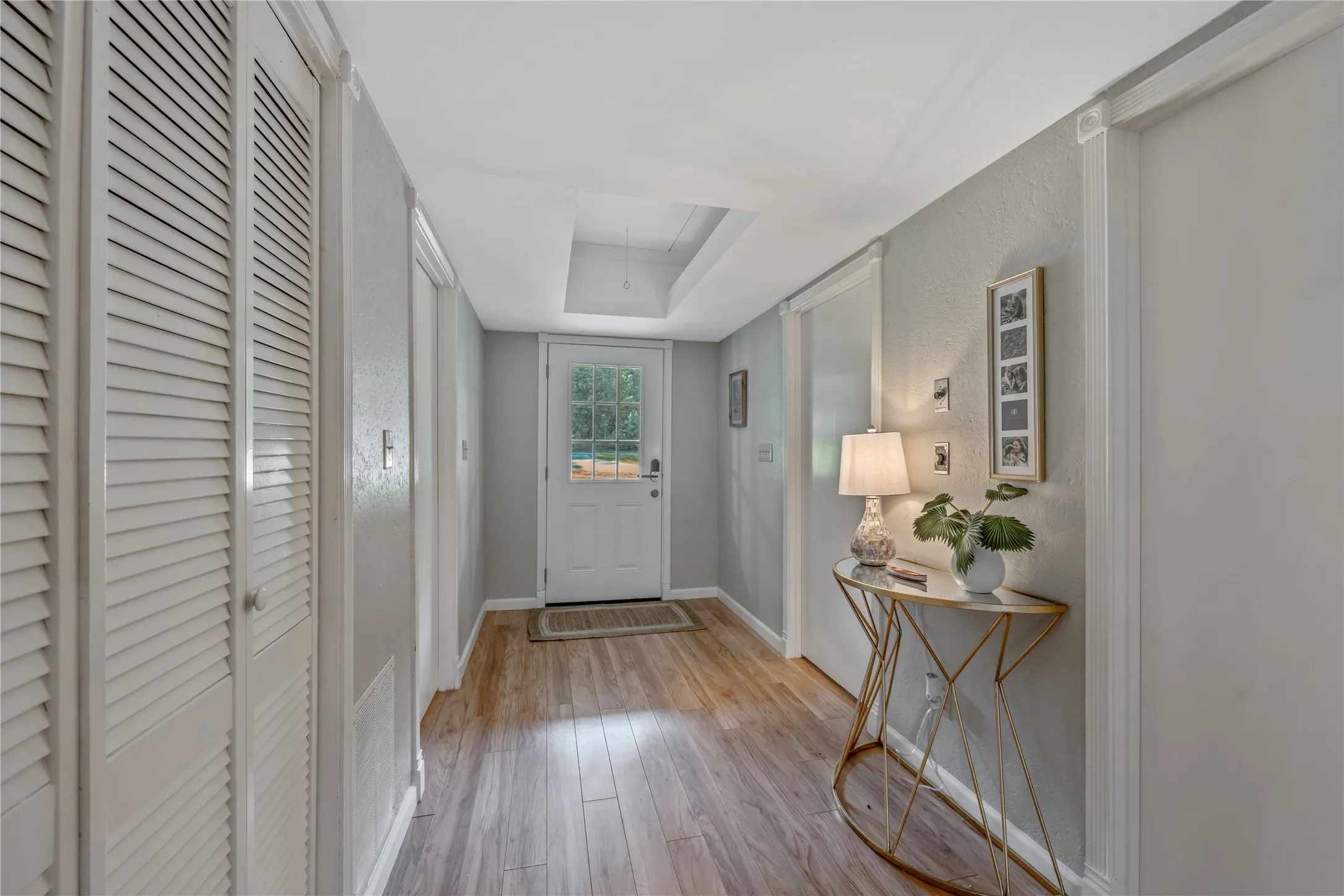 Entryway featuring wood-finish flooring, light gray walls, and white louvered closet doors