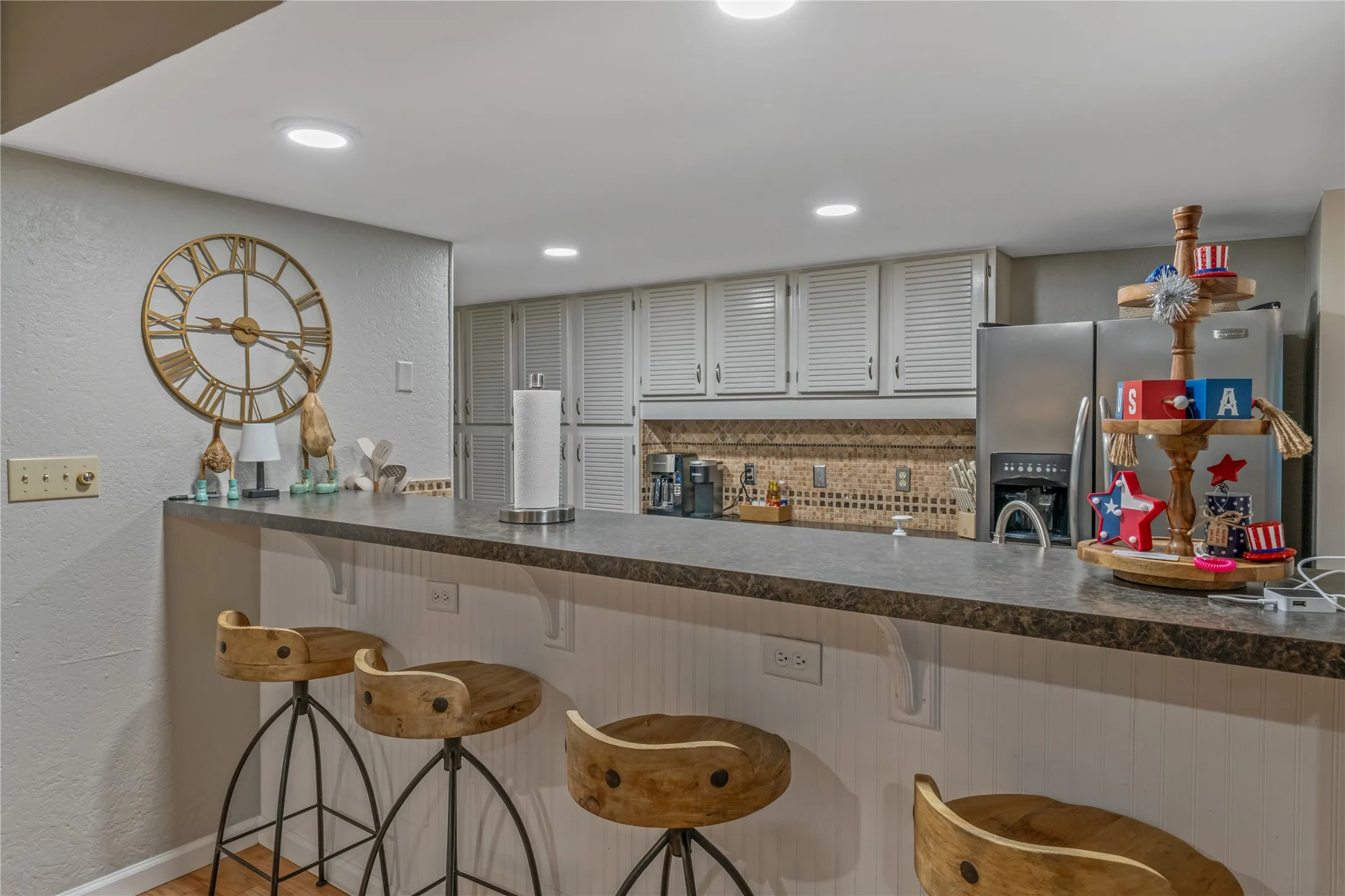 Kitchenette featuring a bar-height counter with a dark speckled surface, white beadboard paneling, and recessed lighting