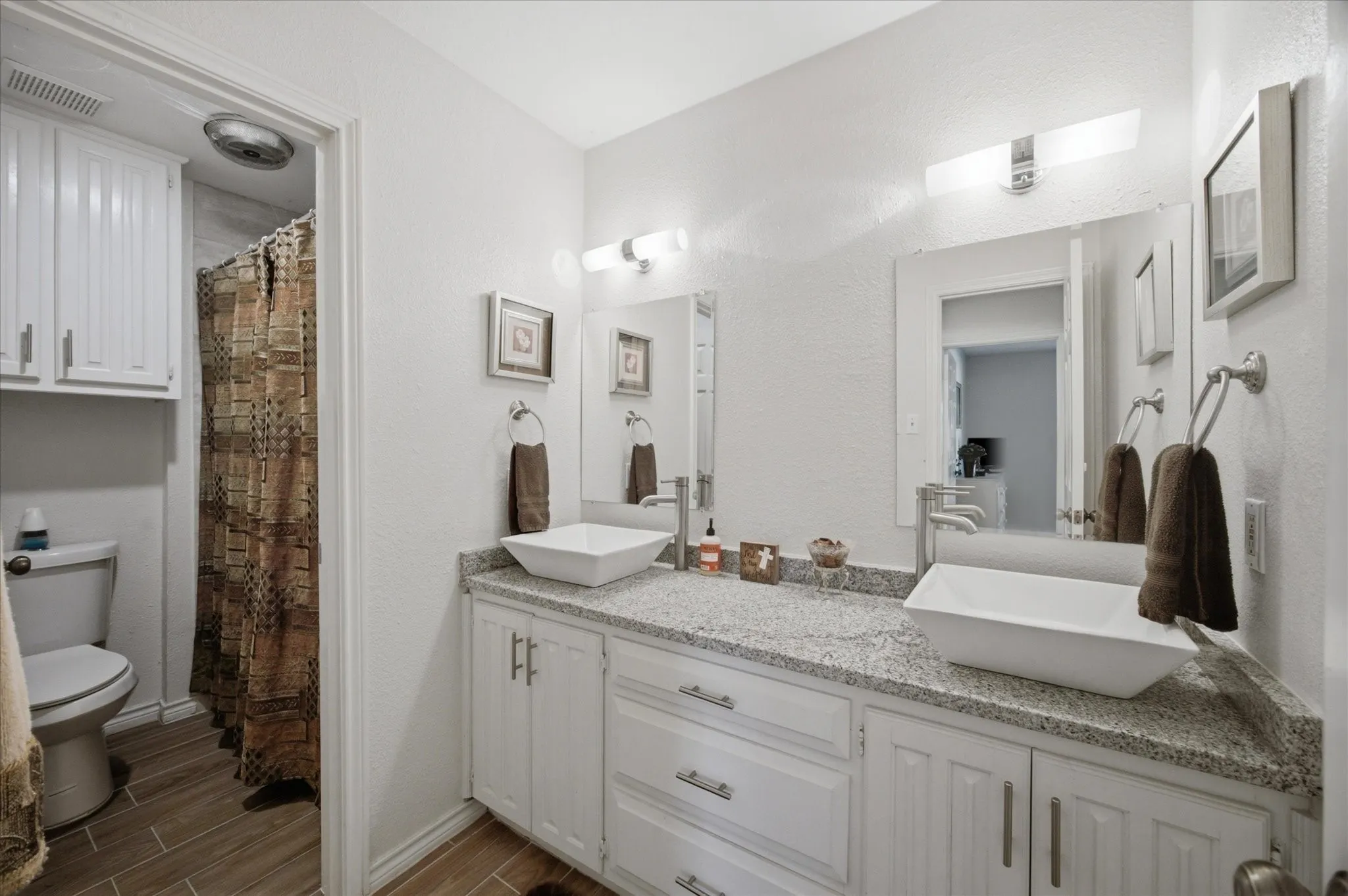 Dual vessel sinks with modern chrome fixtures, set atop a light granite countertop