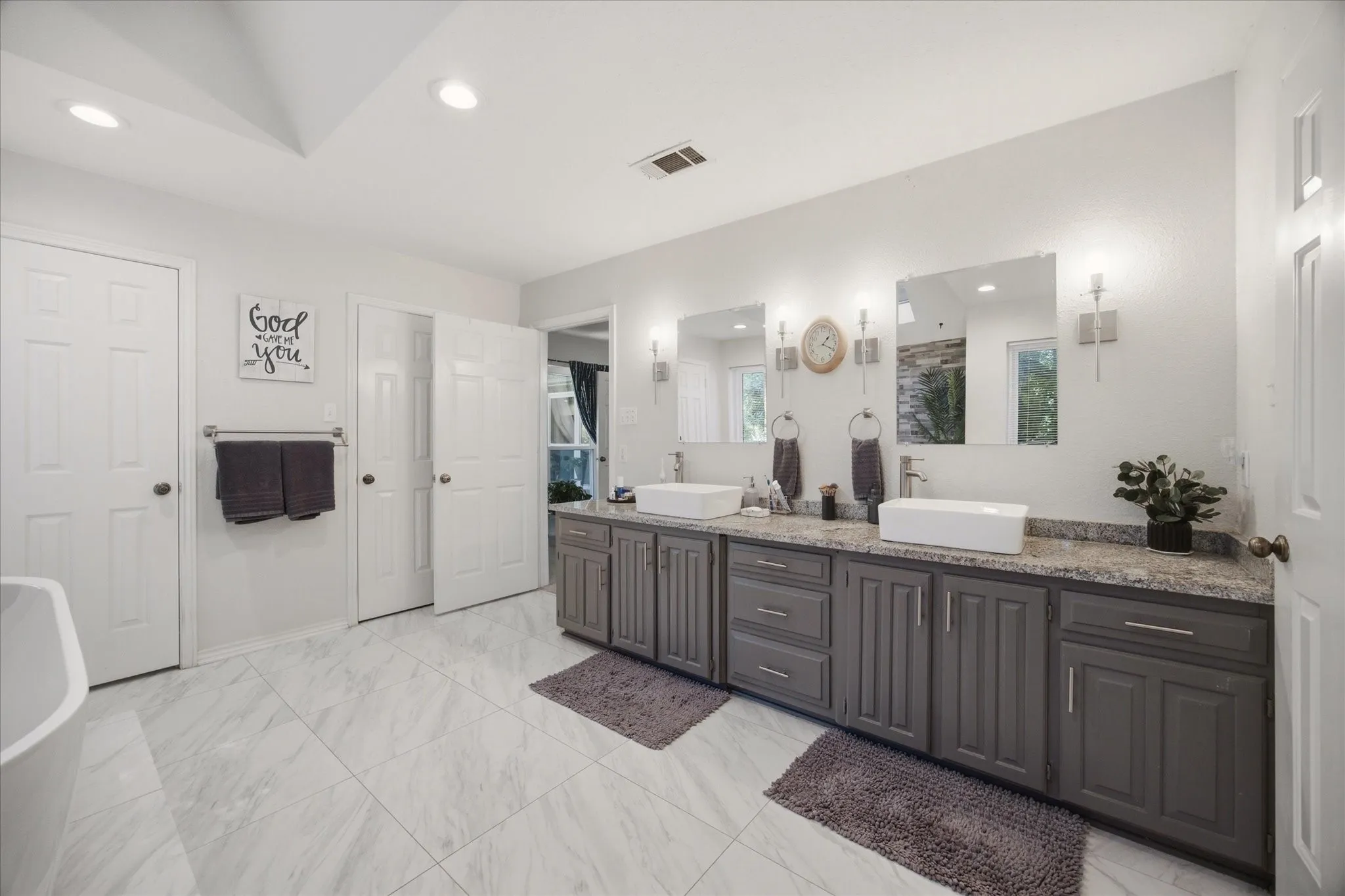 Dual vanity with vessel sinks, stone-finish countertop, and gray cabinetry
