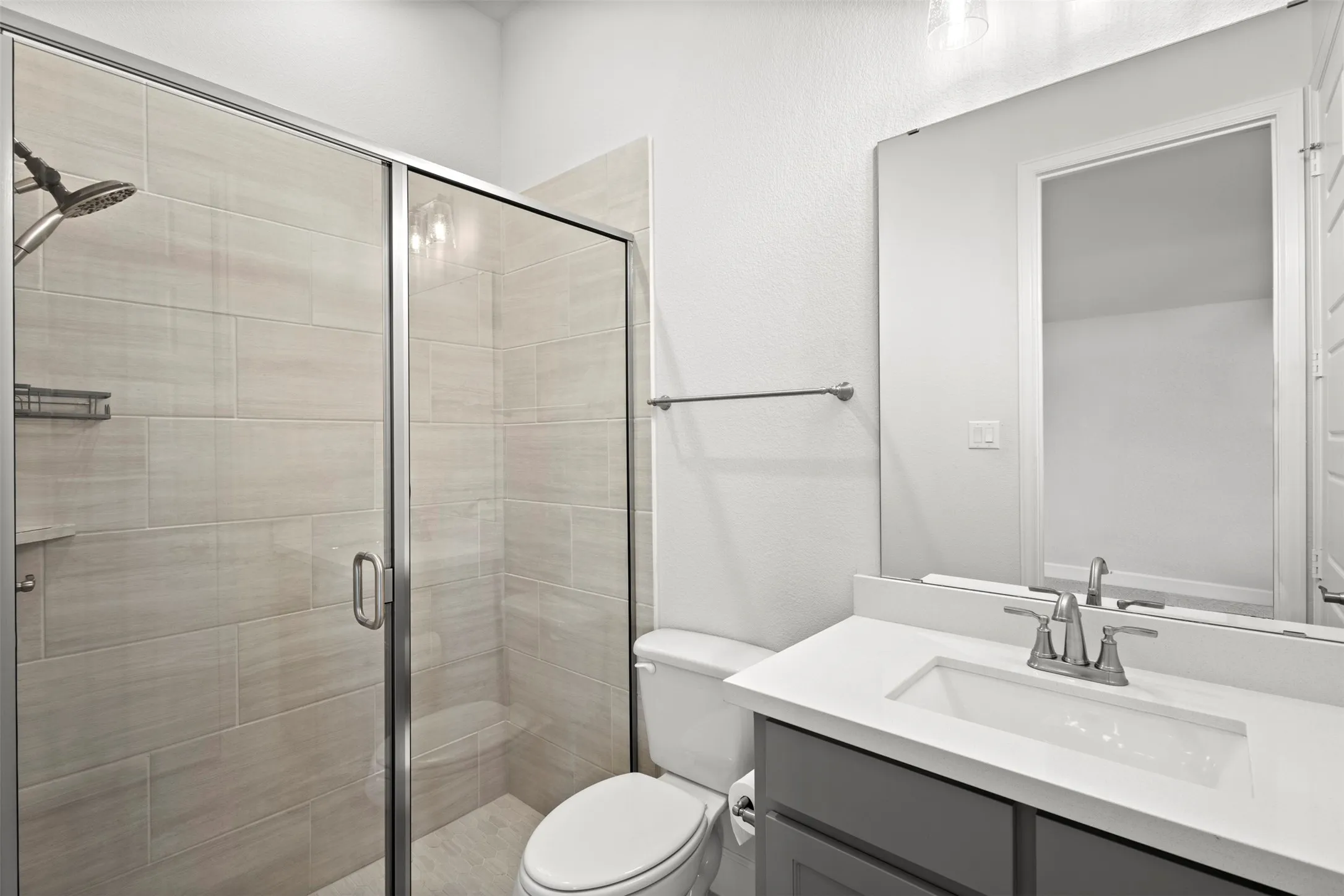 Bathroom featuring a frameless glass shower enclosure with horizontal tile surround, a built-in shower niche, and a shower bench