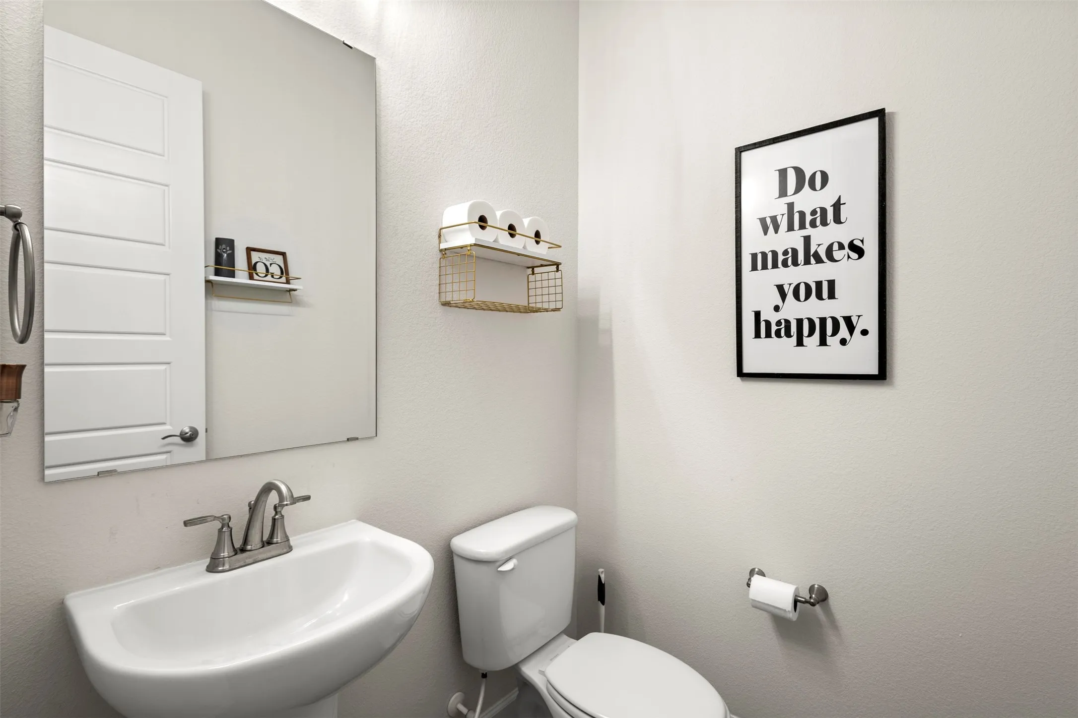 Pedestal sink with chrome faucet, a rectangular wall-mounted mirror, and a white paneled door