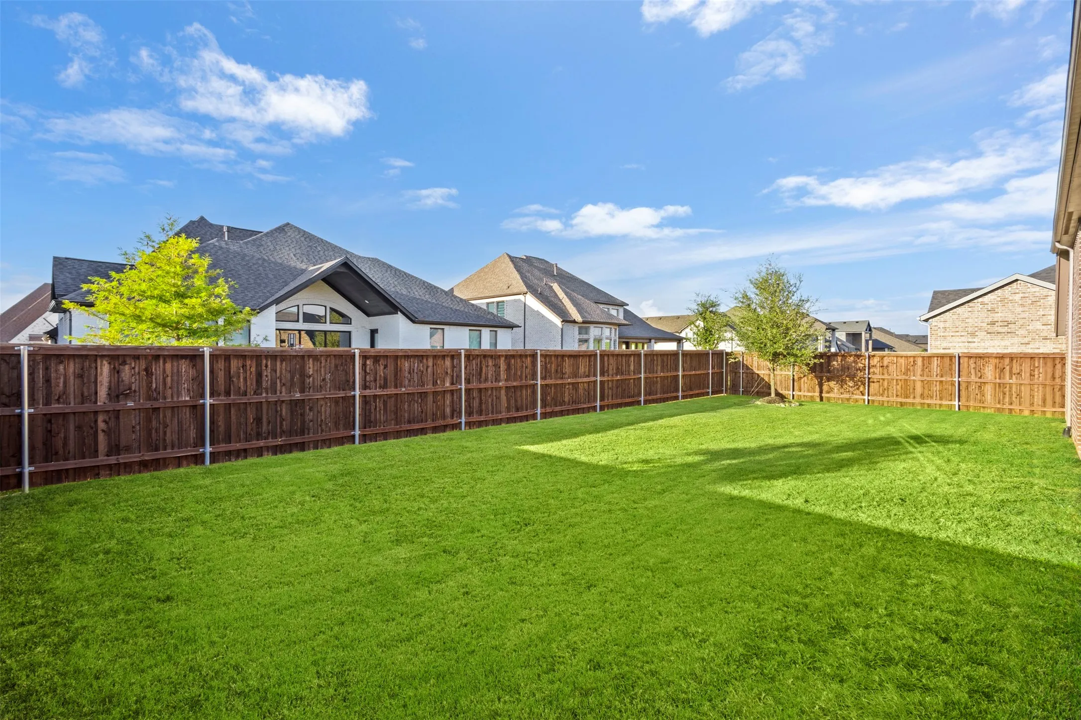 Expansive green lawn with a full wood privacy fence and mature trees