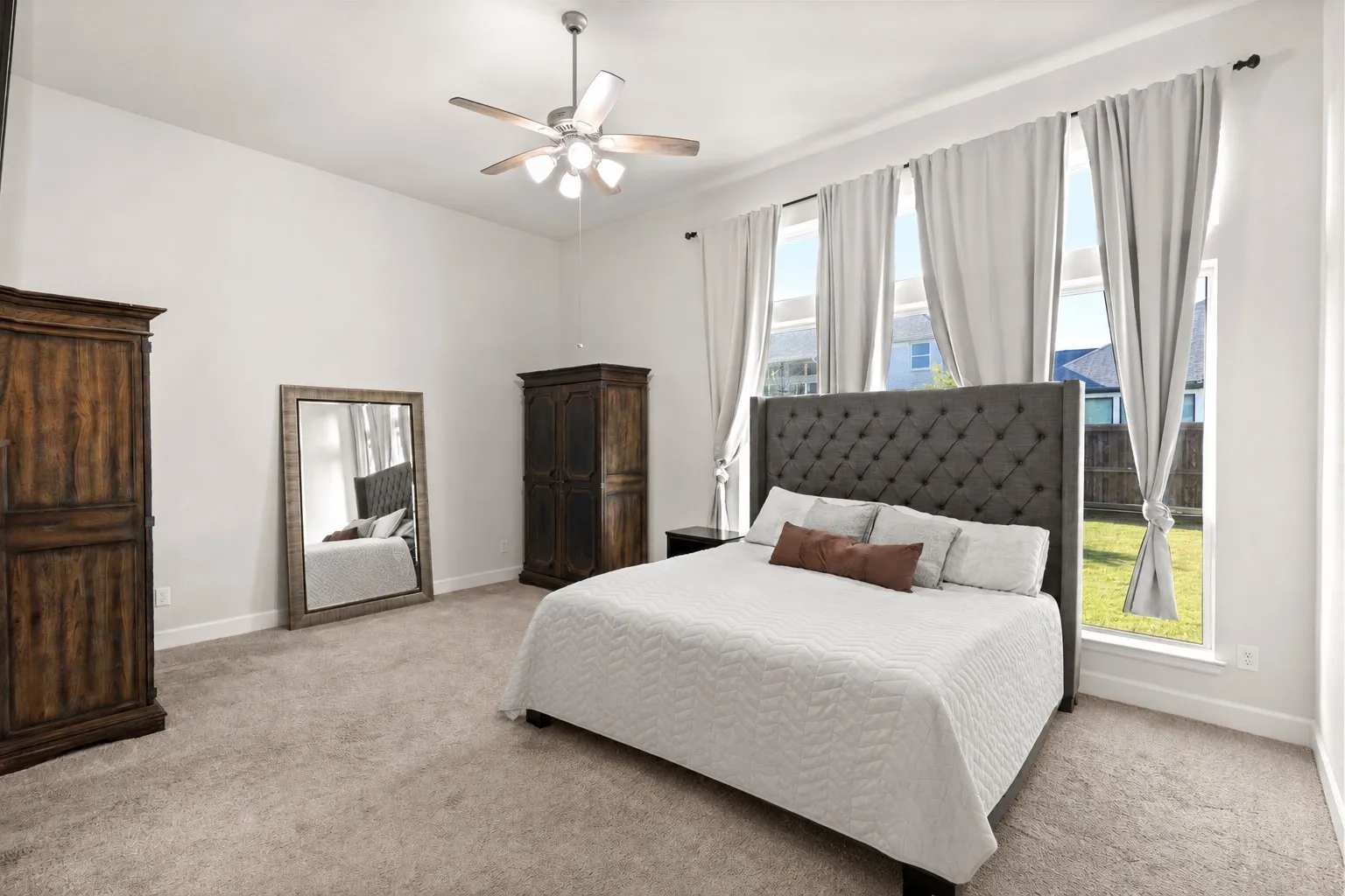Spacious bedroom featuring multiple tall windows, vaulted ceilings, and plush carpet flooring