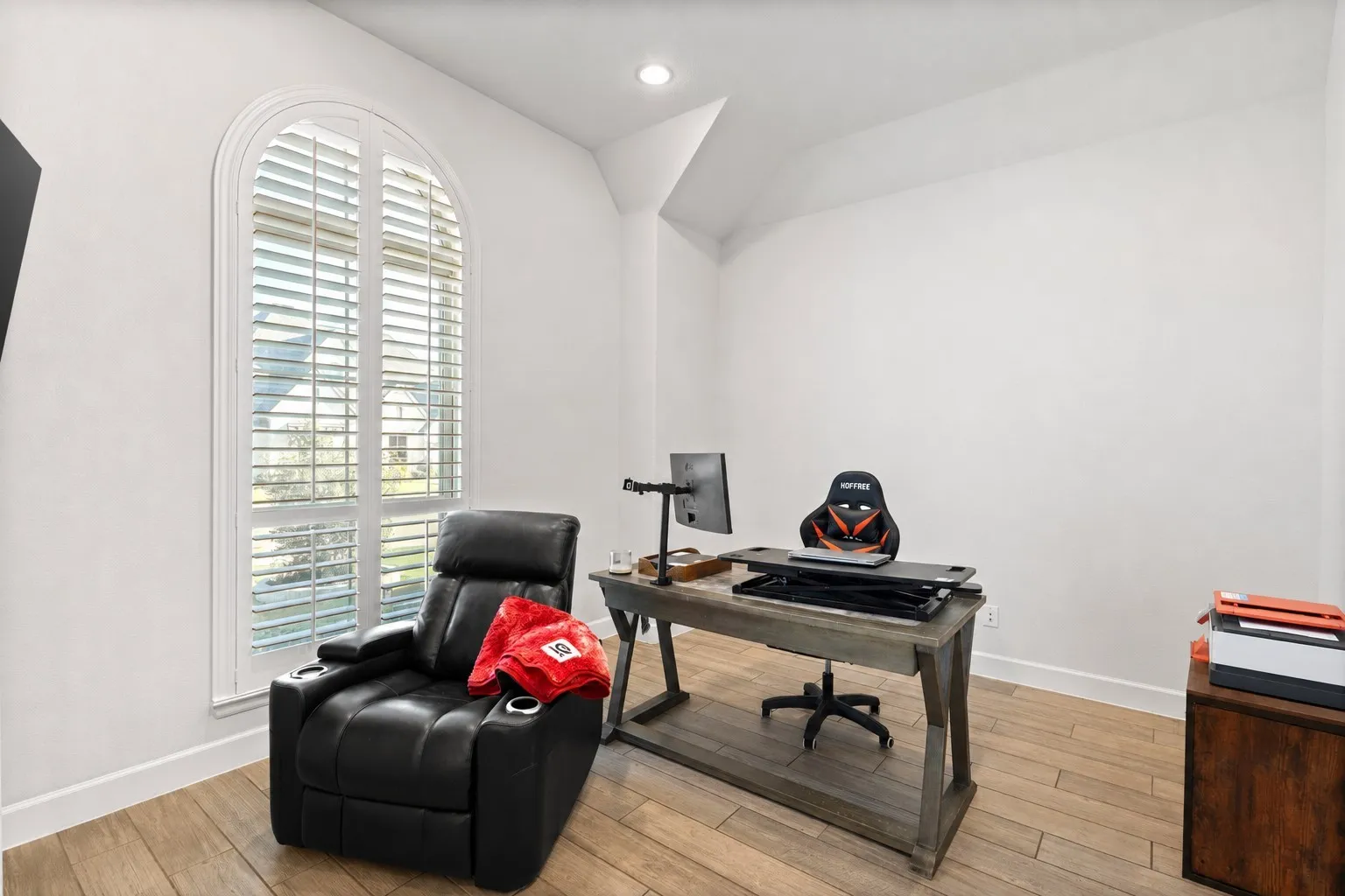 Room featuring an arched window with plantation shutters, wood-finish flooring, recessed lighting, and white baseboards