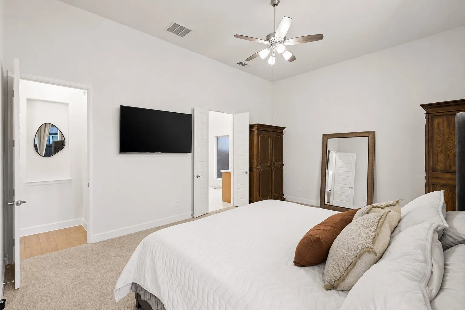 Spacious bedroom featuring high ceilings, a ceiling fan with light fixture, carpeted flooring, and white walls