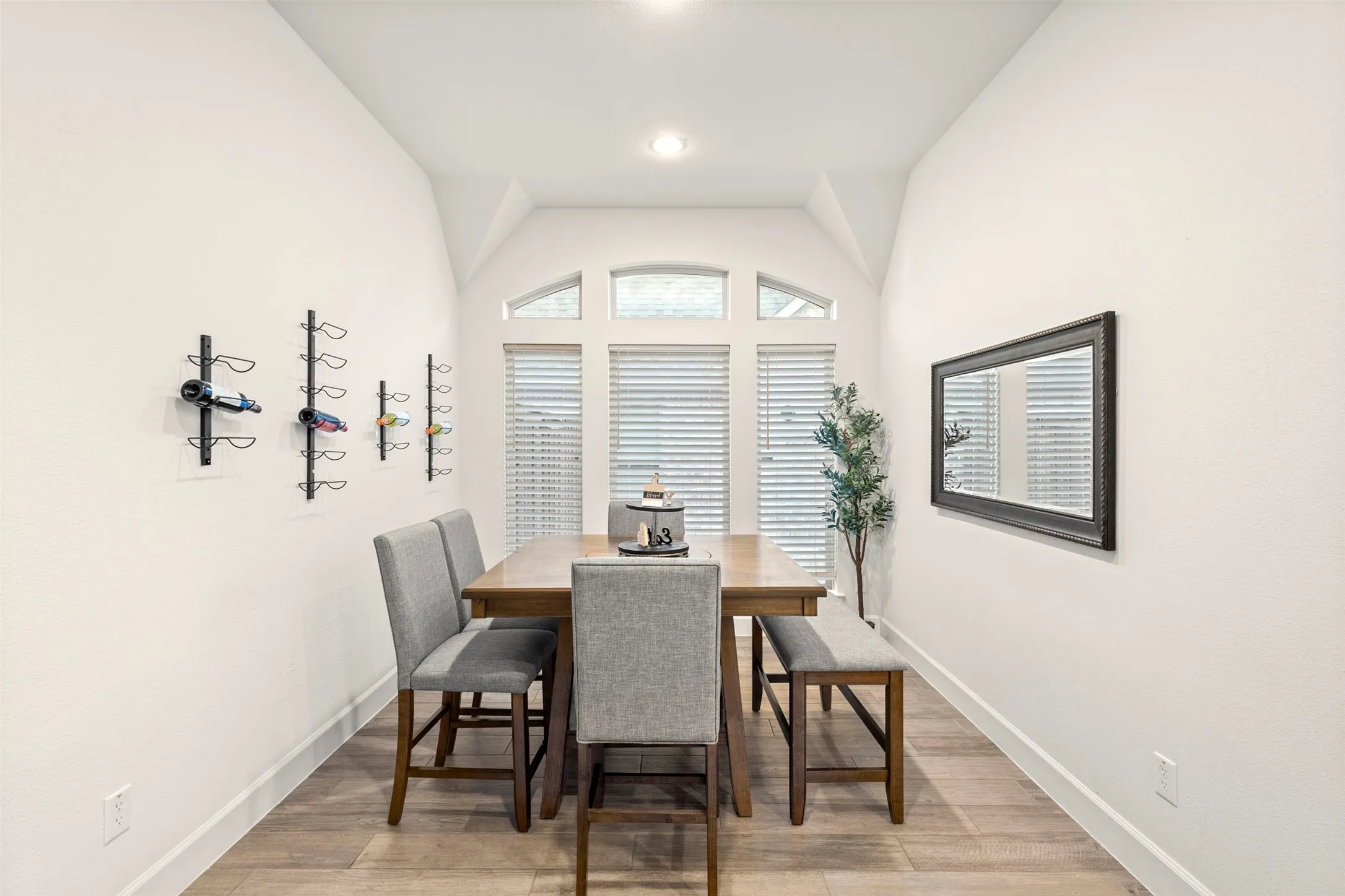 Dining area featuring wood-finish flooring, white baseboards, and a vaulted ceiling