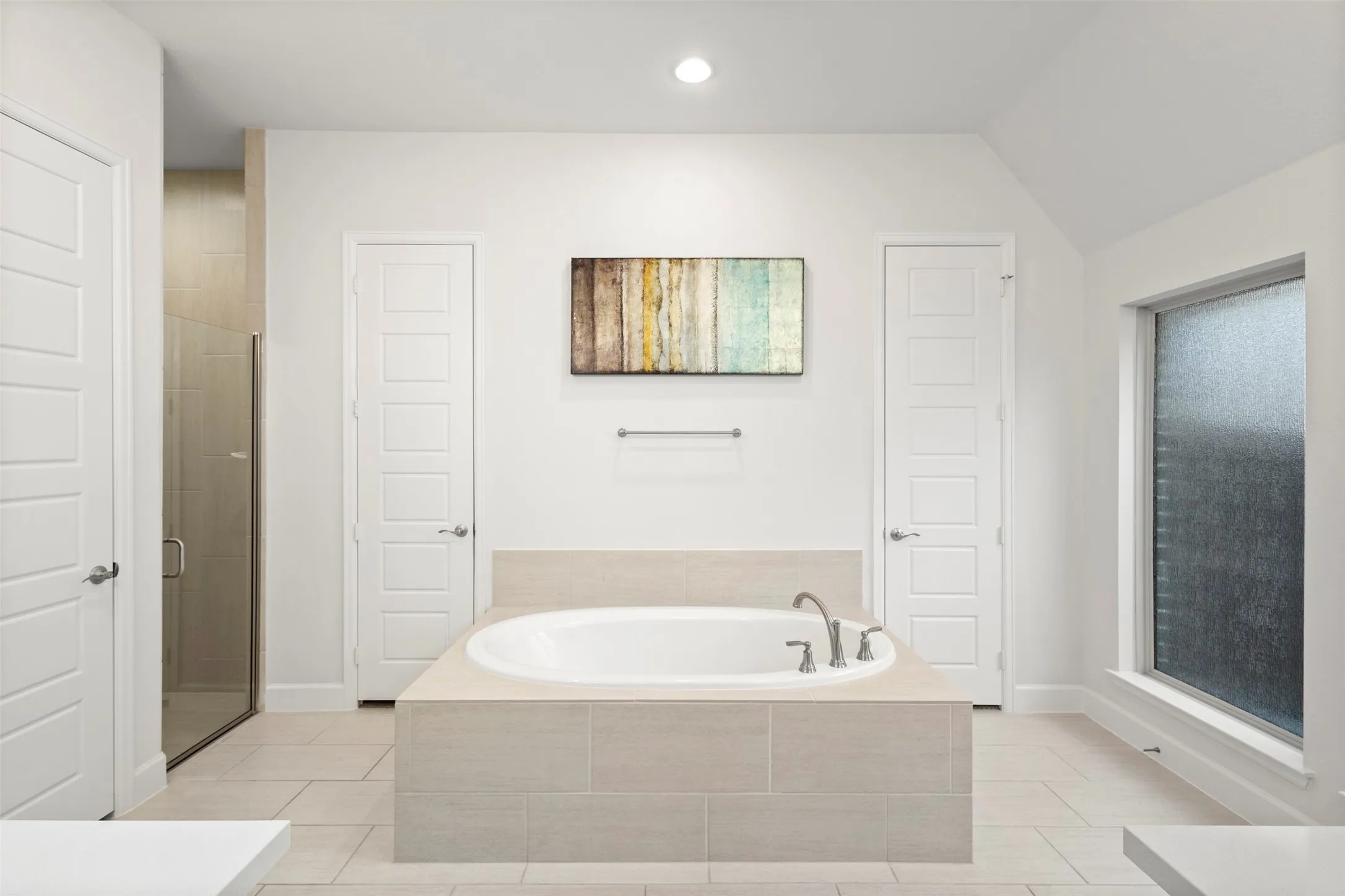Spacious bathroom featuring a built-in soaking tub, a separate glass-enclosed shower, tile flooring, and a frosted privacy window