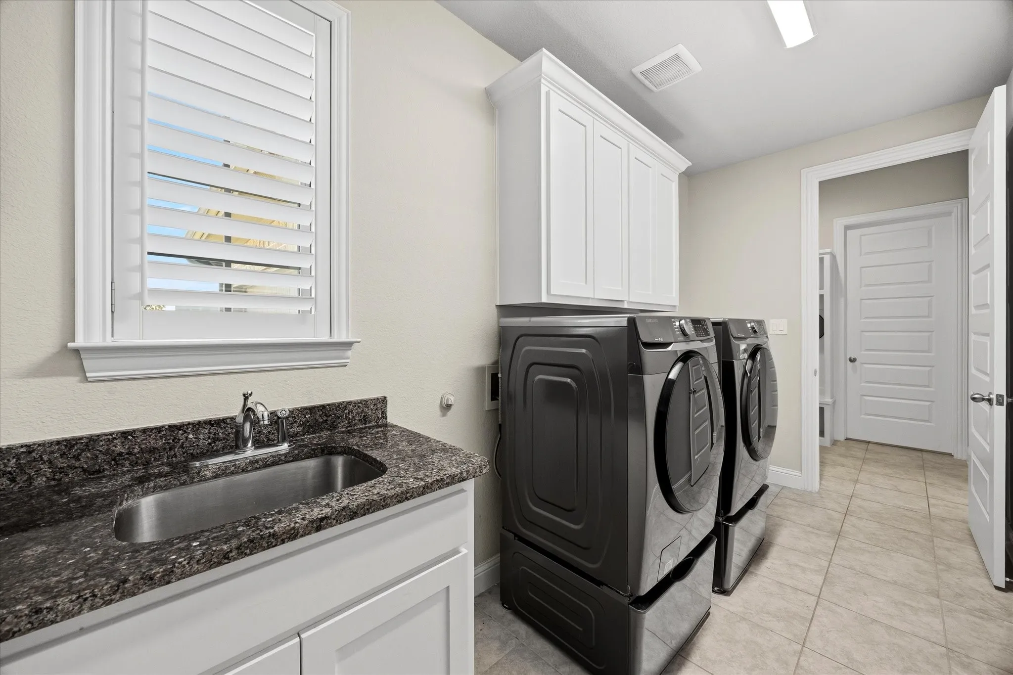 Utiliry room has it all! with sink, custom cabnetry folding area and space for full size washer and dryer!