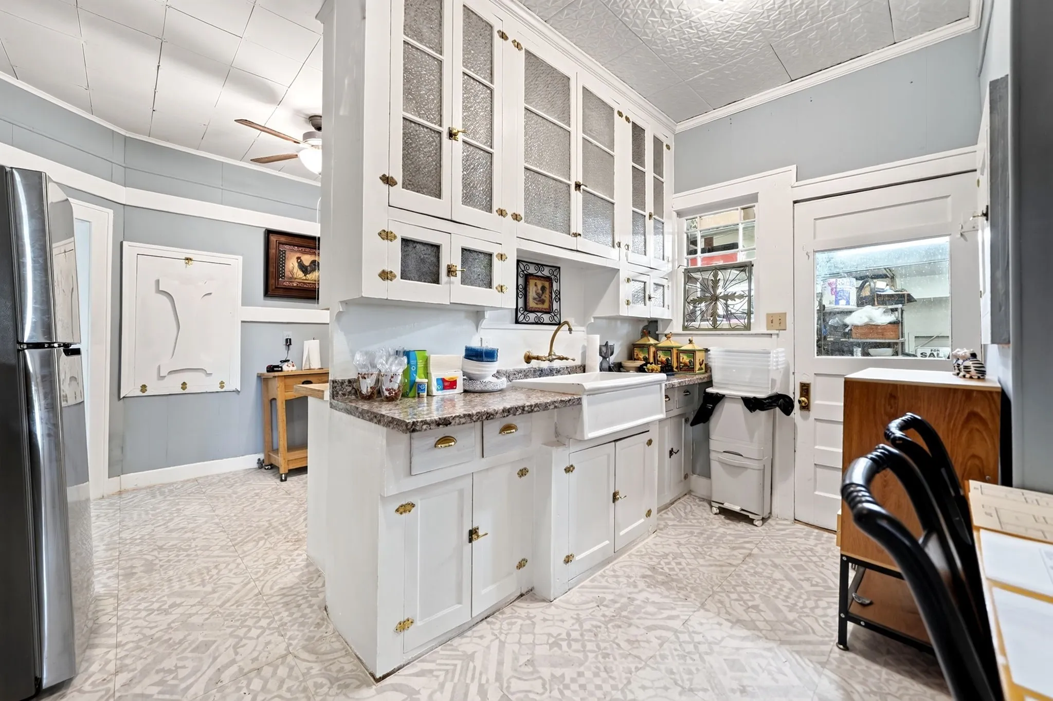 Kitchen featuring white cabinetry with glass-front uppers, a farm sink, and granite-style countertops