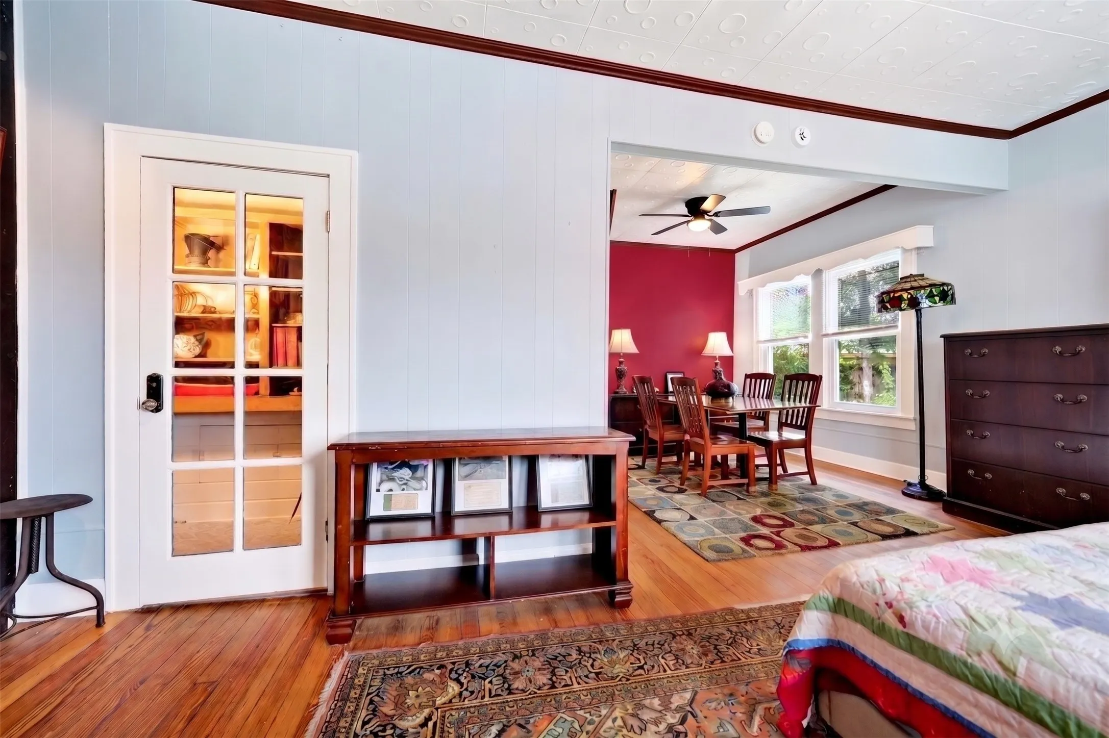Hardwood flooring extending into a dining area featuring a ceiling fan and multiple windows