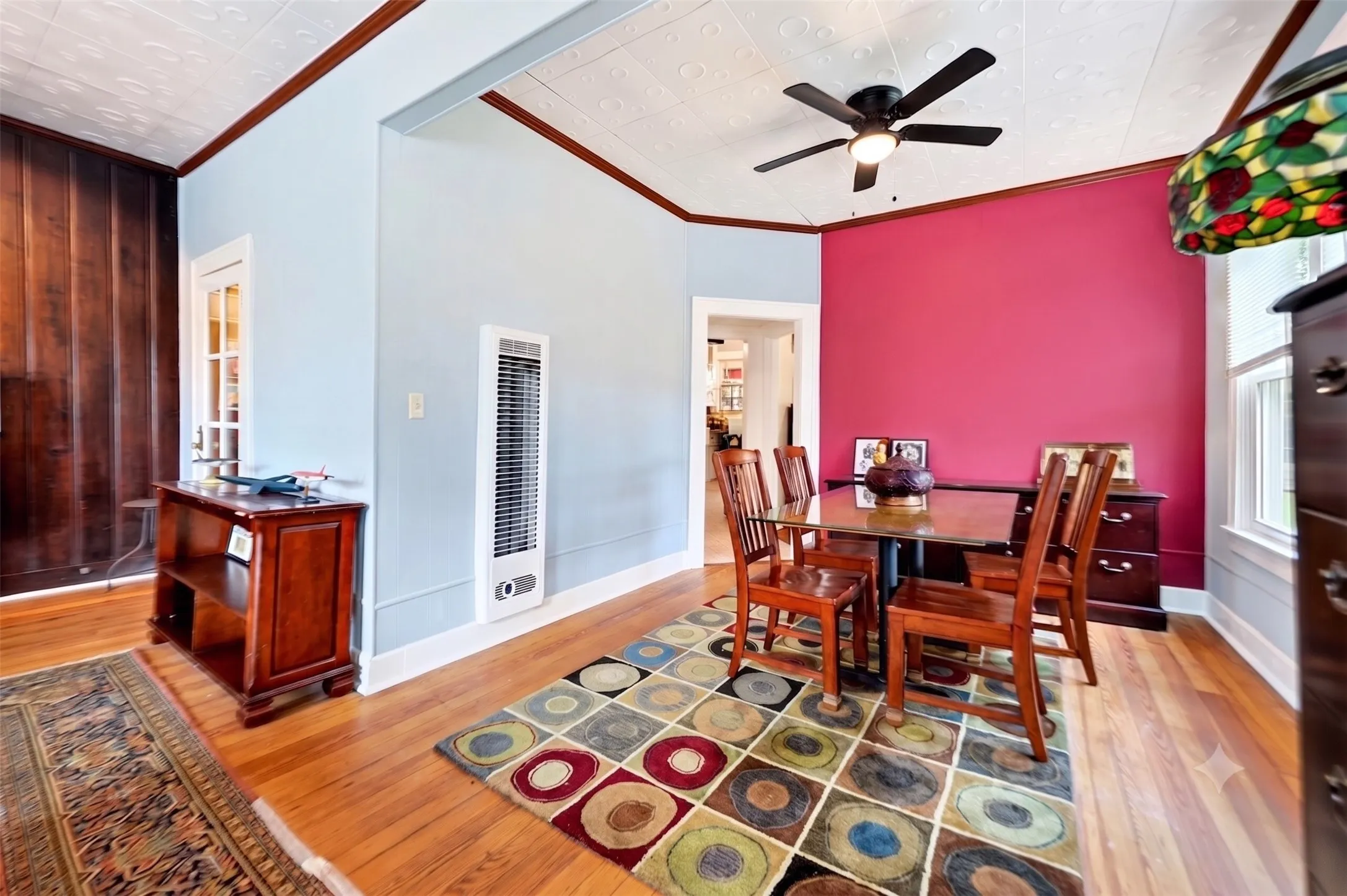 Hardwood flooring with a patterned area rug, crown molding, and a built-in wall heater