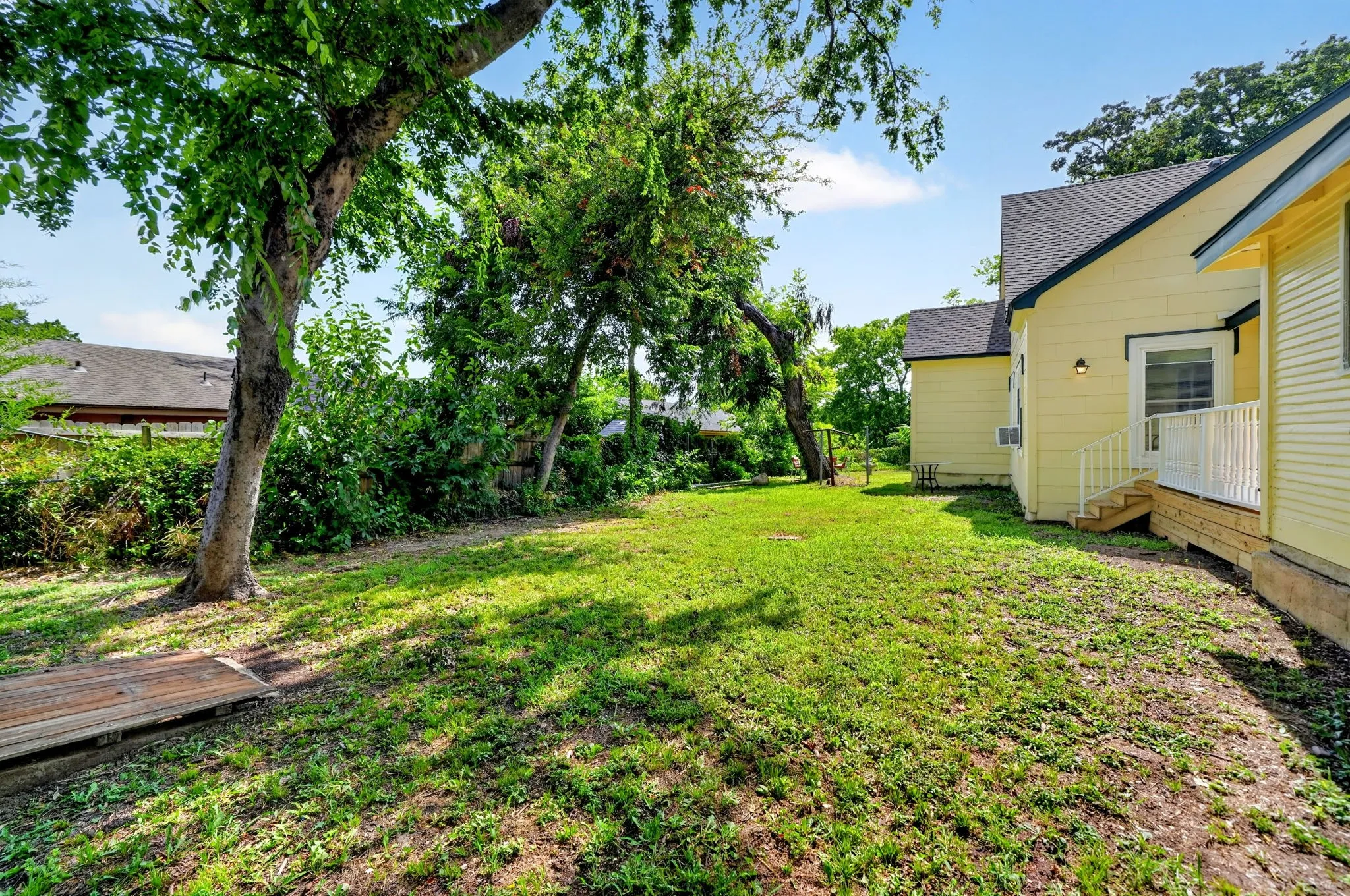 Expansive yard space featuring a lush lawn and mature trees