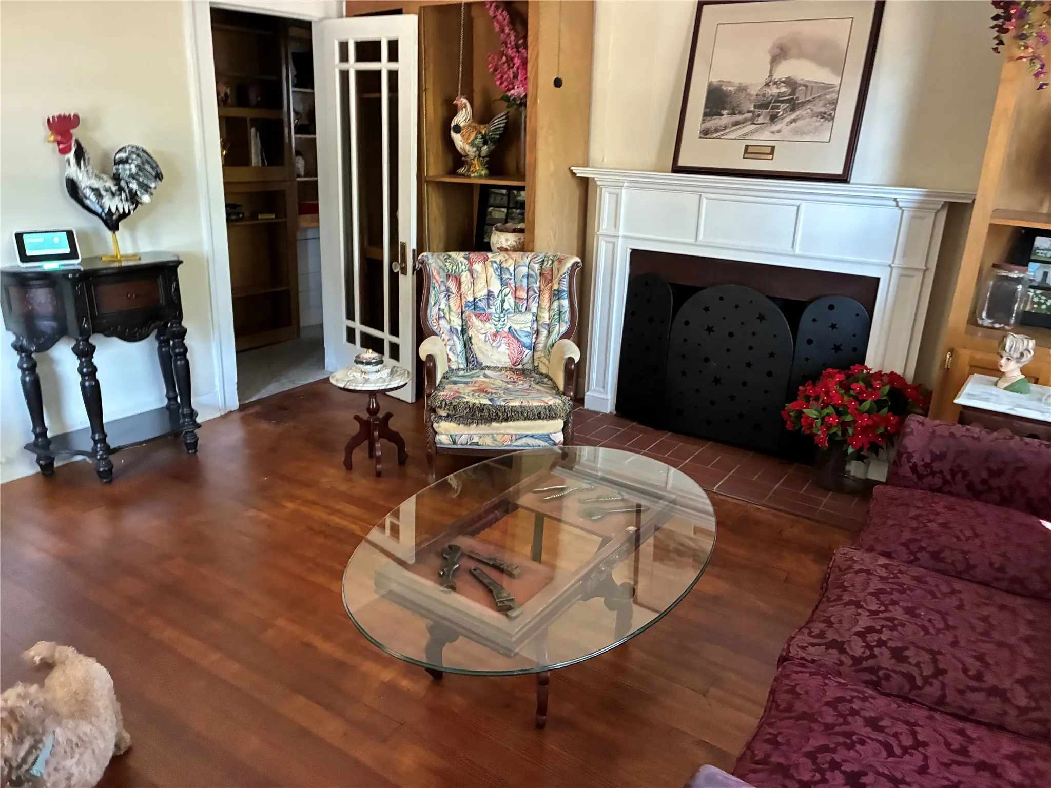 Hardwood flooring, white fireplace mantel, brick fireplace hearth, built-in shelving, French doors