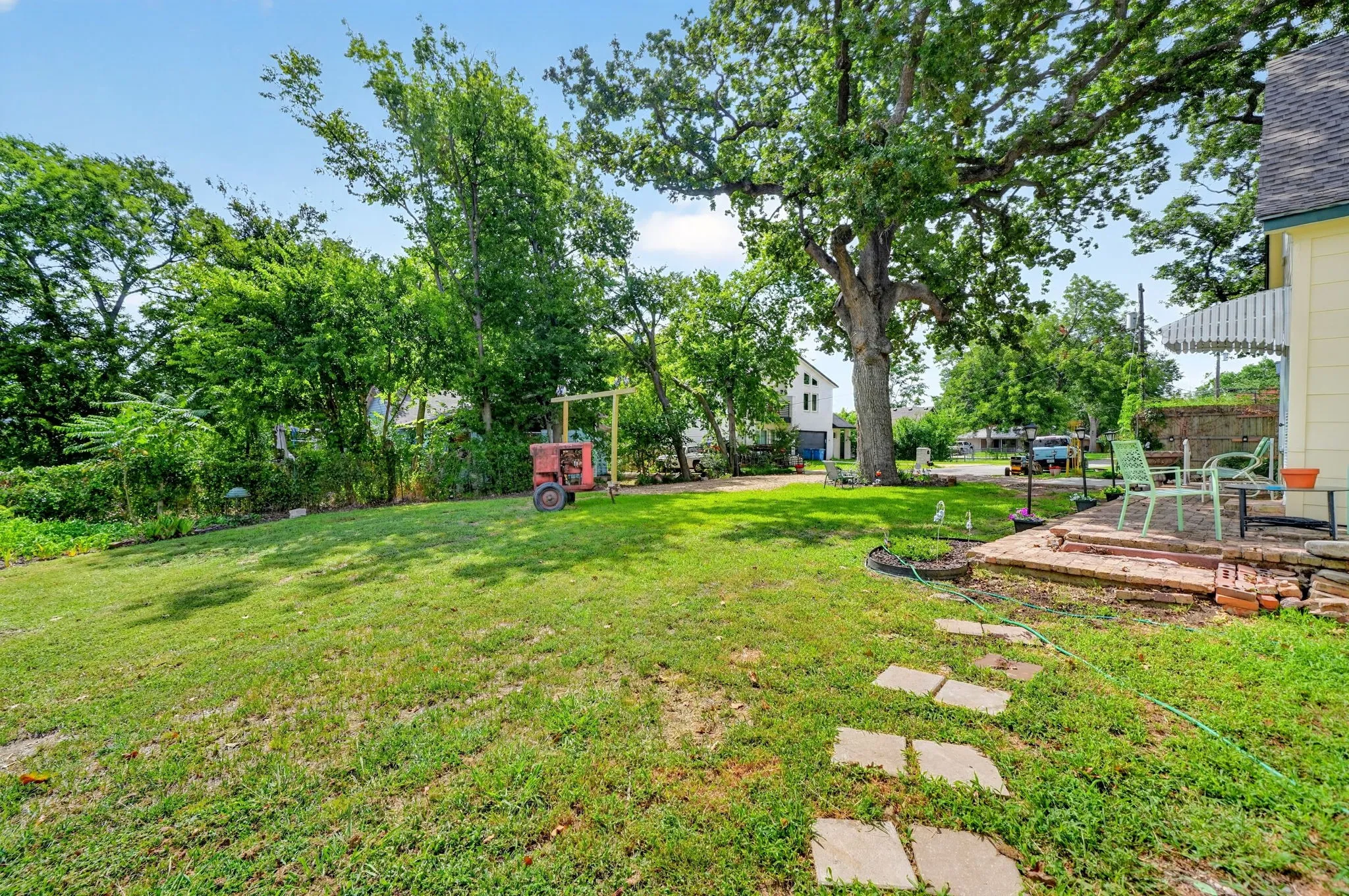 Expansive lawn area featuring mature trees and a stone paver pathway