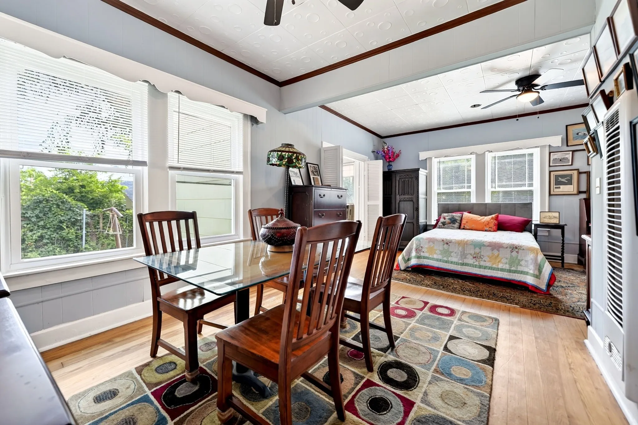 Hardwood-style flooring extends throughout this open room, featuring a dining area with a glass-top table and a separate sleeping area