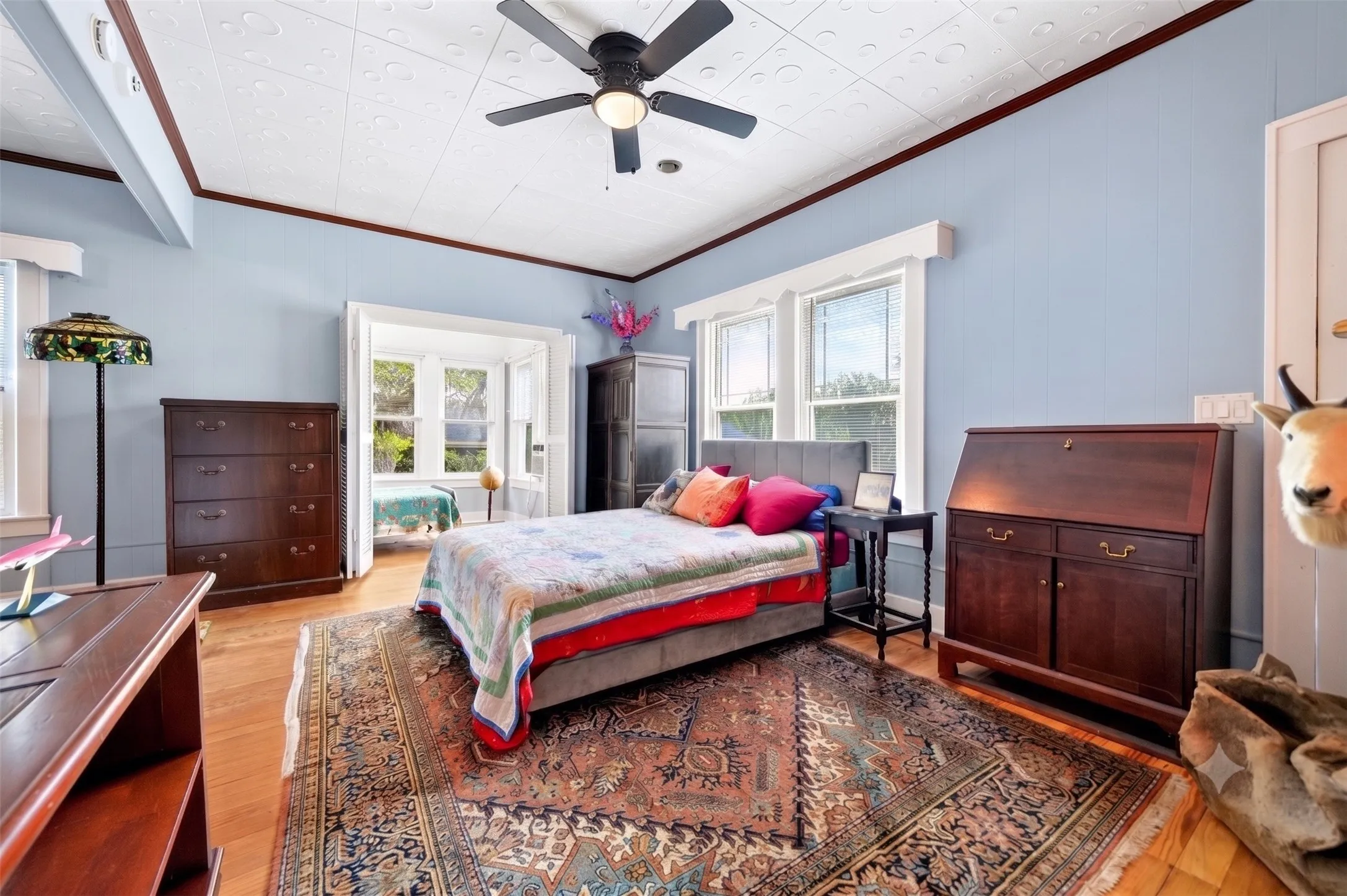 Hardwood flooring complements a decorative pressed tin ceiling with a ceiling fan