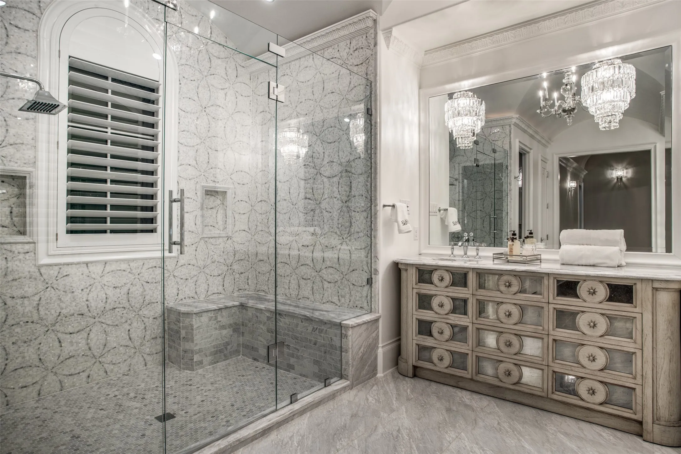 The primary shower features a rain shower head and body sprays, along with a convenient bench.  The elegant tile is unique and beatiful.