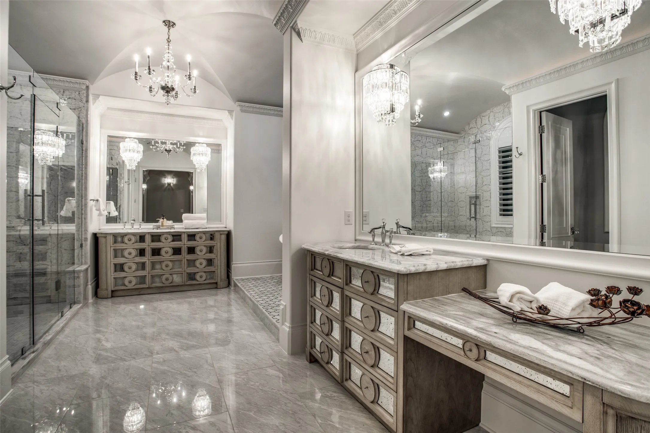The luxurious primary bath features crystal chandeliers and sconces, separate vanities, separate shower and soaking tub.