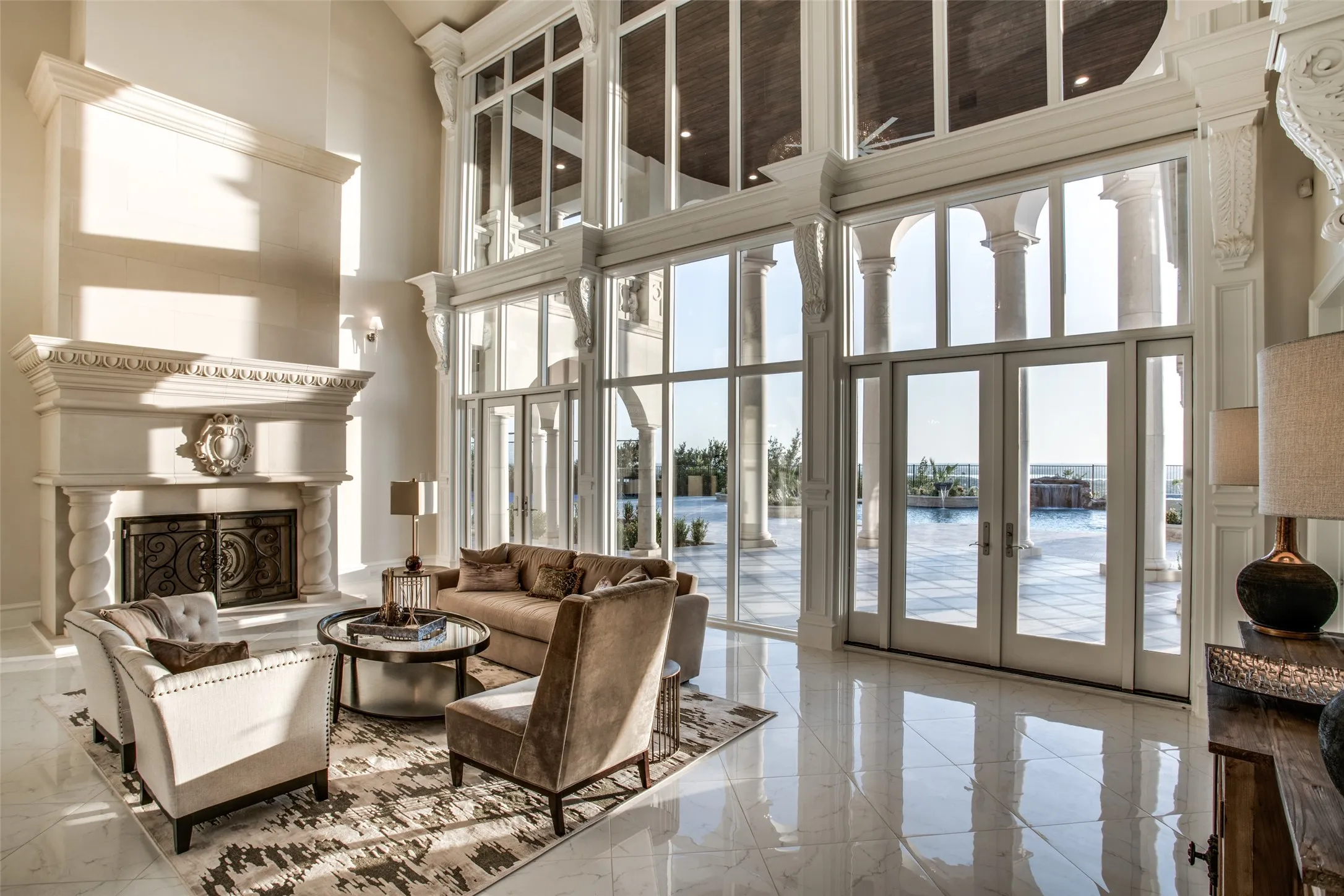The grand, two story formal living room features a huge fireplace to warm guests while they look through the walls of windows (featuring electric shades) to the resort-style pool and breathtaking views.