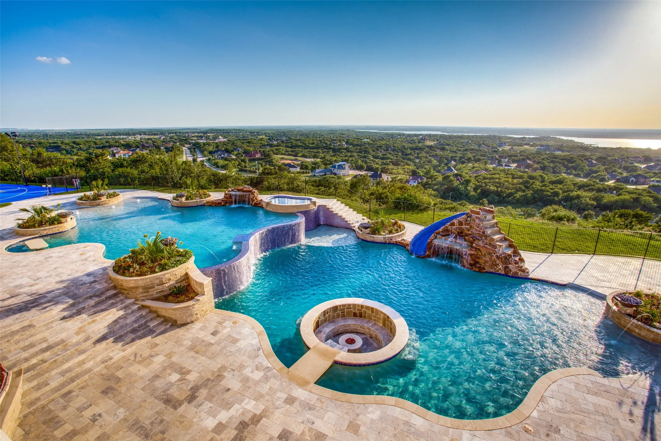 The pool features two grottos for escaping from the sun and enjoying the waterfalls splashing over you.  Also notice the sunken fire pit in the foreground and the spa and water slide in the background!