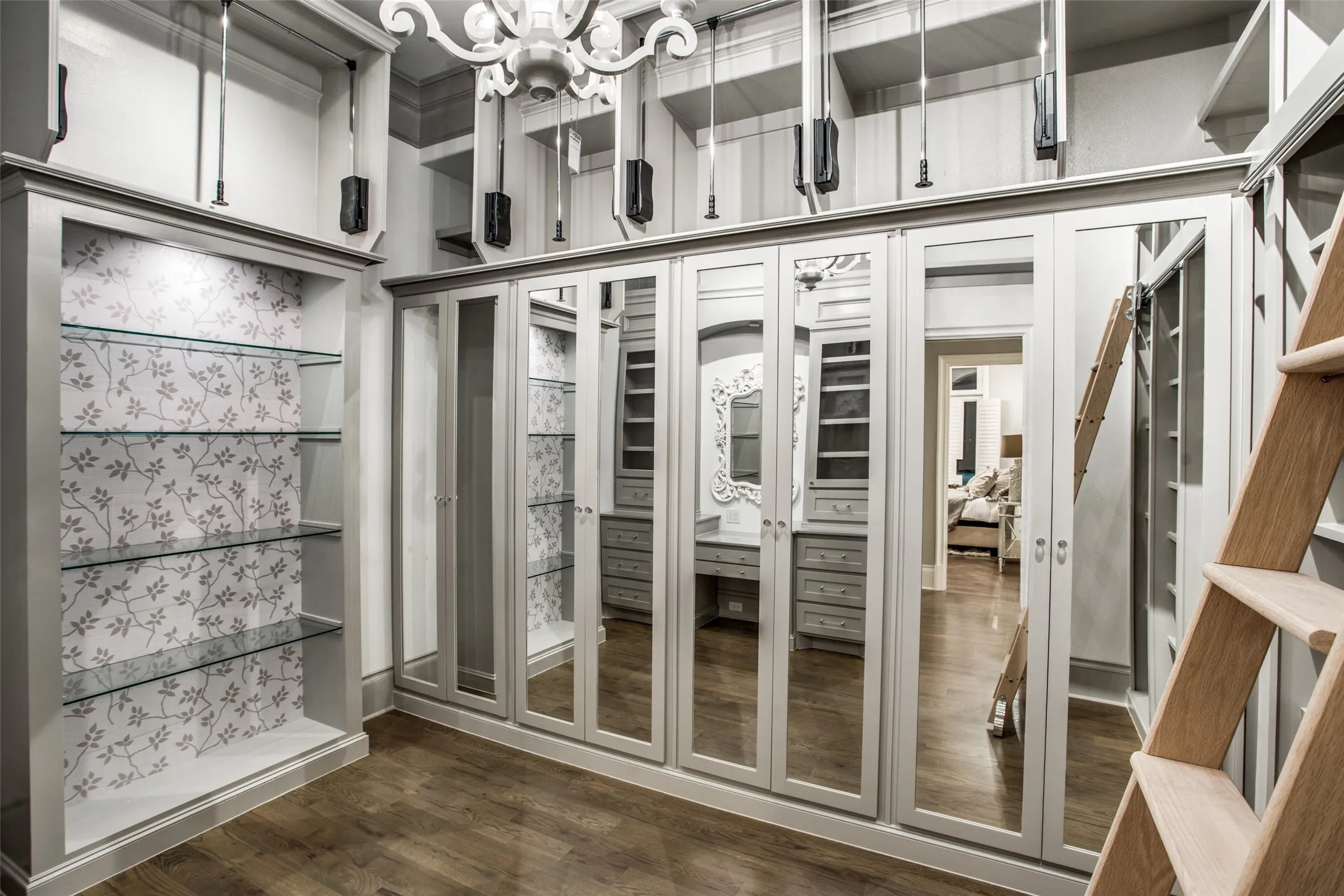 One of the two primary suite closets with custom cabinets, pull down storage racks and mirrored cabinet doors.