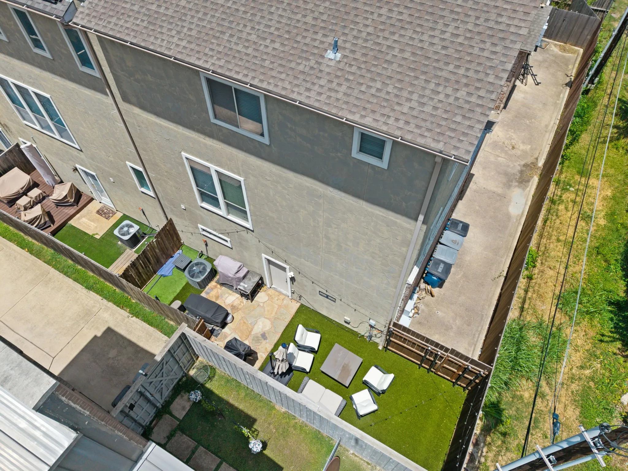 Rear exterior featuring a stone patio, artificial turf, and a wood privacy​​‌​​​​‌​​‌‌​‌‌​​​‌‌​‌​‌​‌​​​‌​​ fence