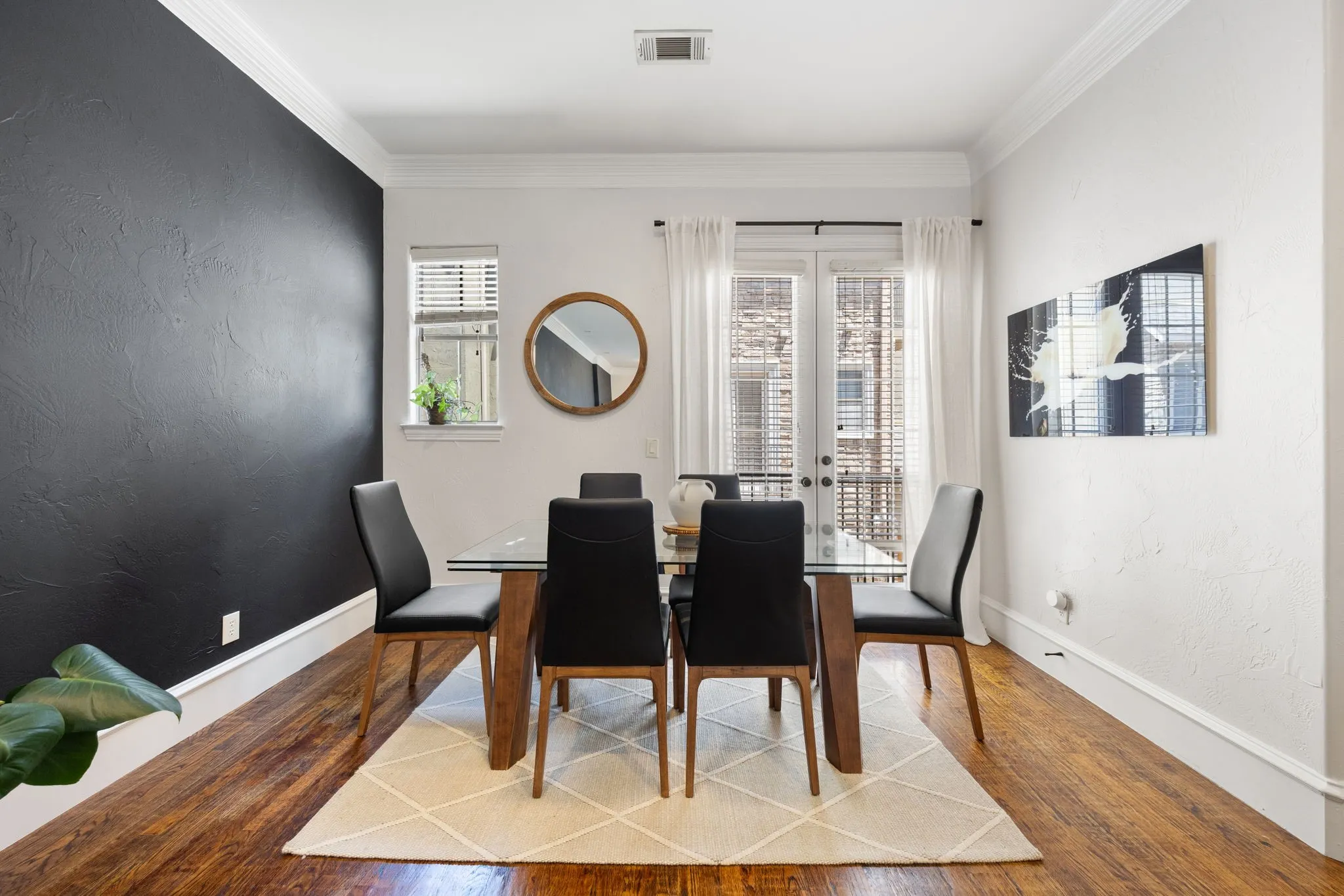 Dining area featuring rich wood-finish flooring and a contrasting accent wall