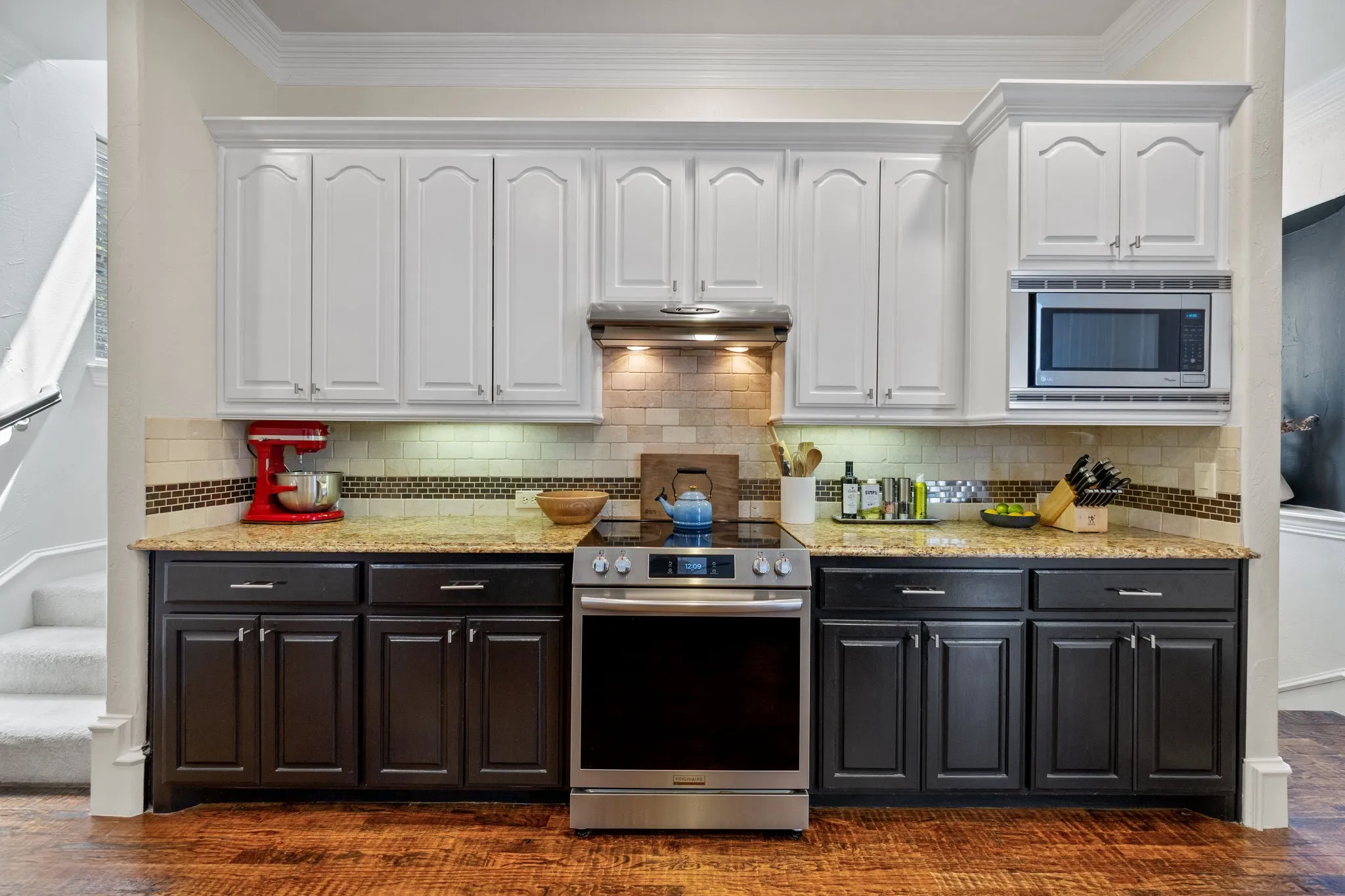 Kitchen featuring two-tone cabinetry with white upper cabinets and dark lower cabinets, a stainless steel range, and a built-in microwave