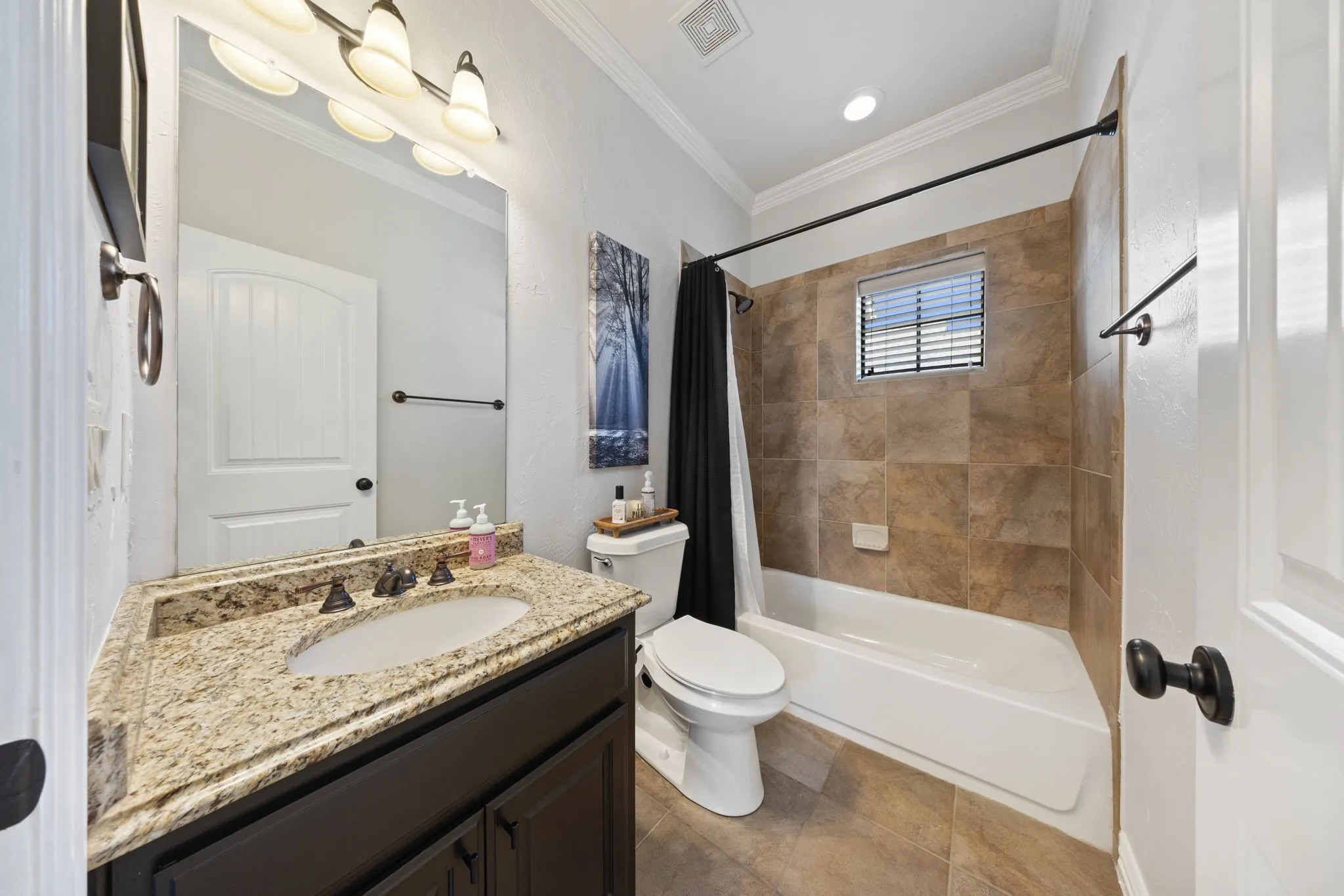 Bathroom featuring a single vanity with a light-toned countertop, an integrated sink, and dark wood cabinetry