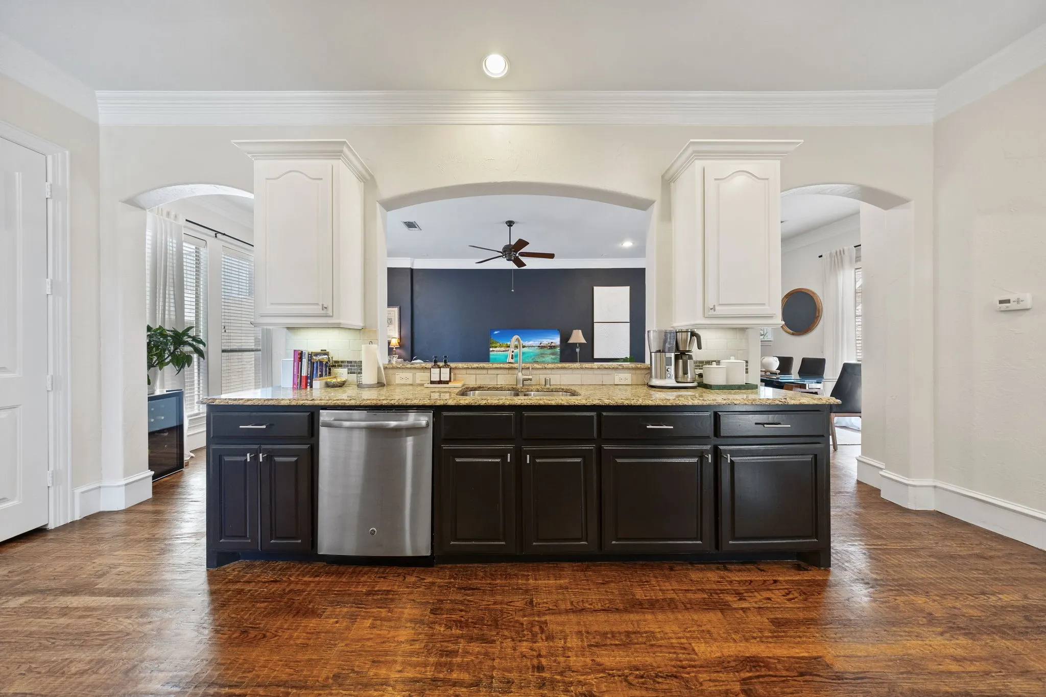 Kitchen island featuring dark wood cabinetry, a stainless steel dishwasher, and a light-toned countertop