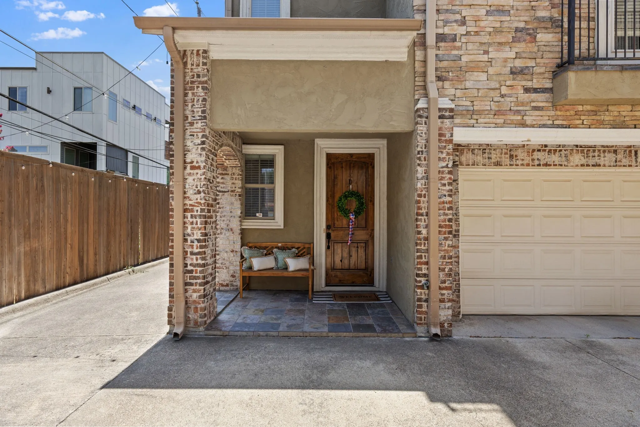 Covered entry featuring a rustic wood door, stone tile flooring, and a single window