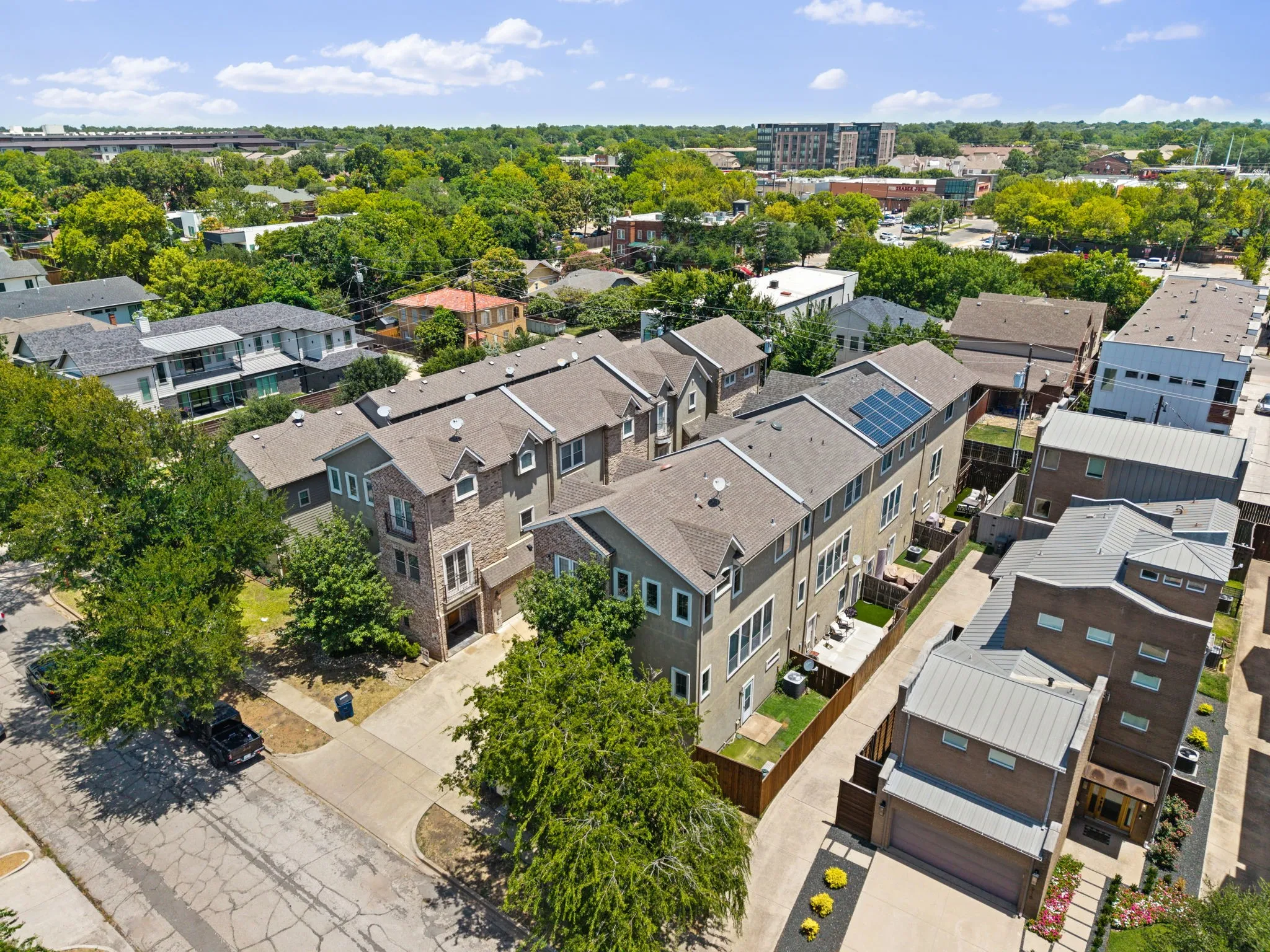 Contemporary townhome community featuring brick and siding facades, gabled roofs with dormers, and private outdoor patios