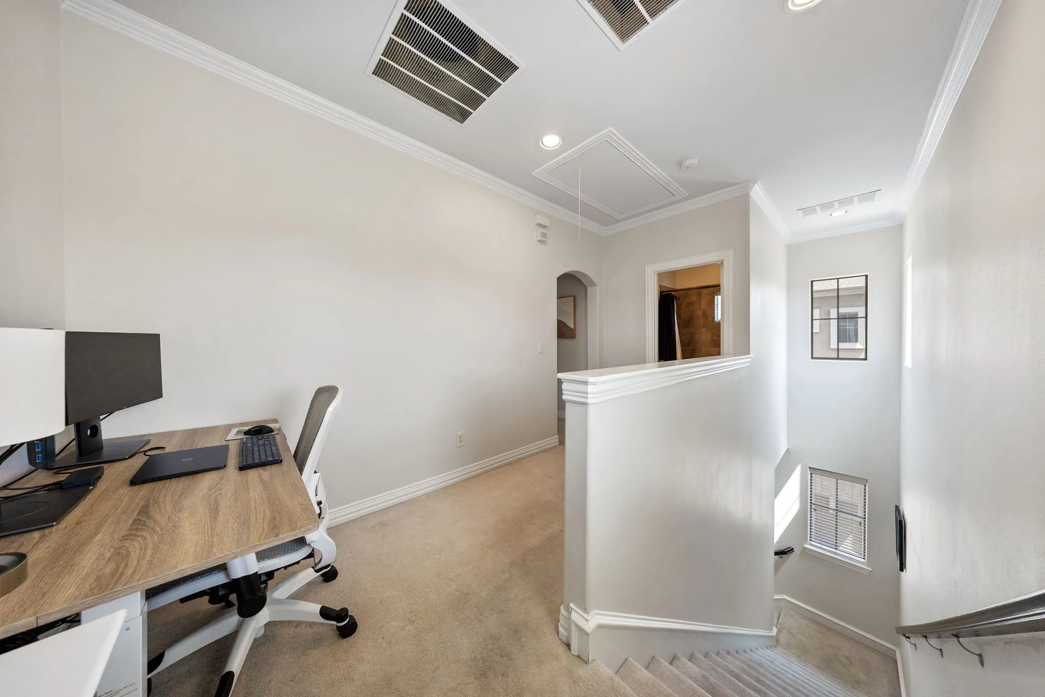 Carpeted second-story landing with crown molding, recessed lighting, and a white balustrade