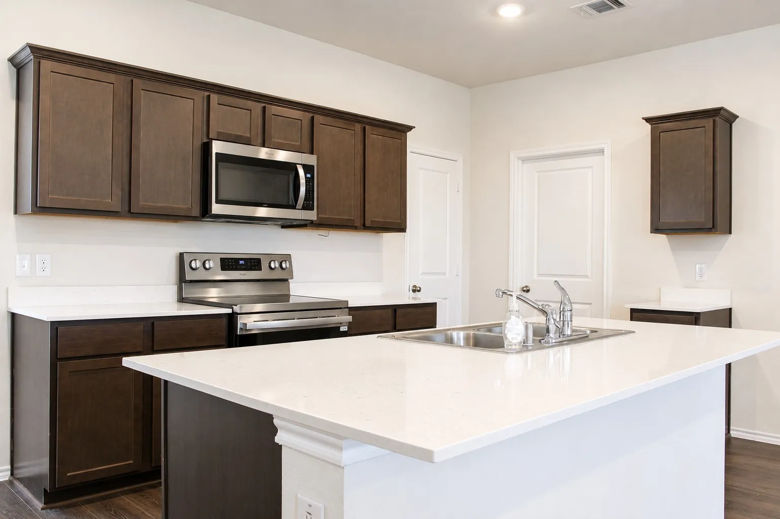 Kitchen featuring a central island with an undermount stainless steel sink and a single-handle faucet